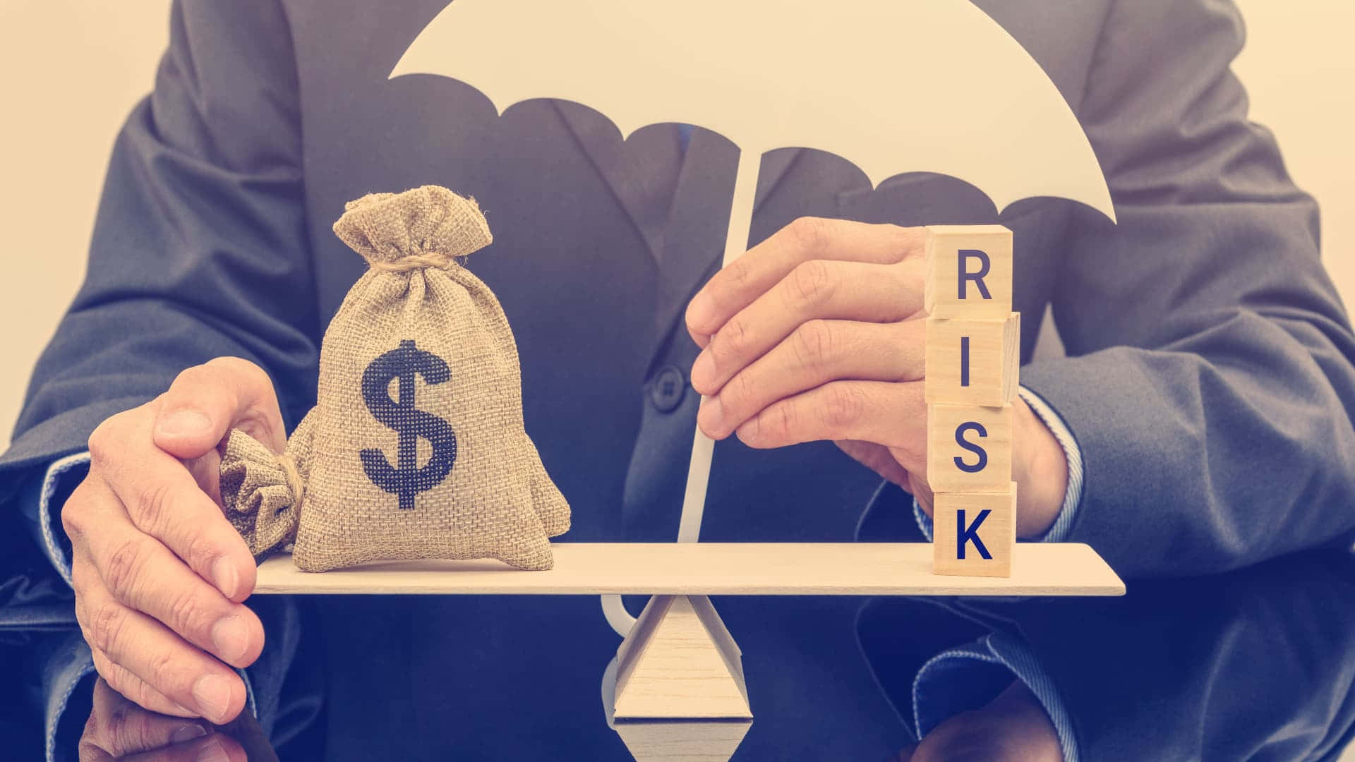 金錢 桌布 壁紙 — 一名商人拿著雨傘遮住一個錢袋和平衡在蹺蹺板上的風險方塊。