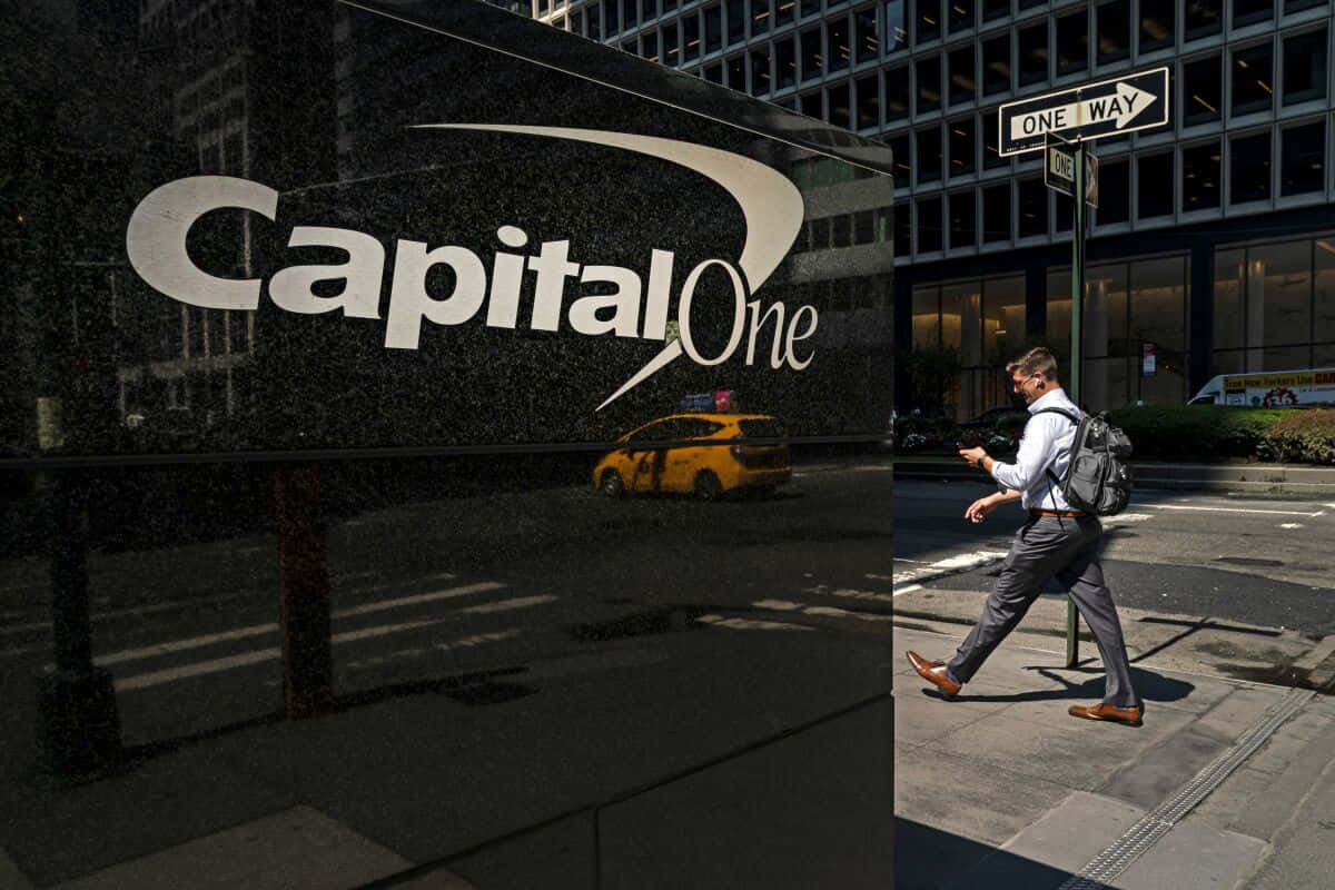 Man 桌布 壁紙 — 一名商人走過 Capital One 大樓，一輛黃色計程車在明亮的日光下反射在其玻璃外牆上。