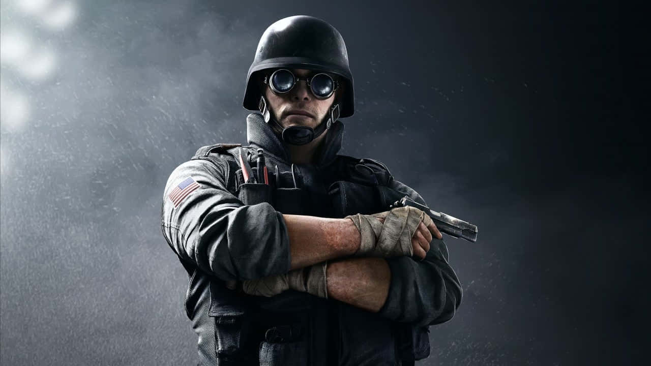 Rainbow Six Siege Thermite 桌布 壁紙 — 一名嚴肅的士兵戴著頭盔和護目鏡，雙臂交叉，手持手槍，背景是煙霧瀰漫的黑暗環境。