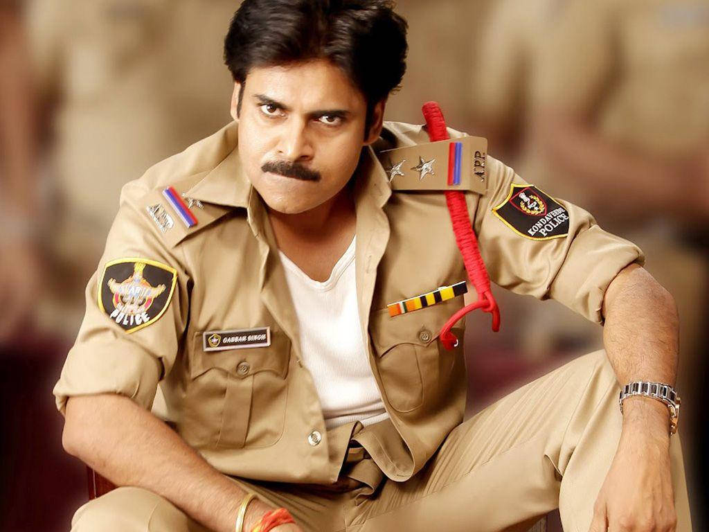 Pawan Kalyan 桌布 壁紙 — 一名嚴肅的警察穿著卡其色制服，手持紅色警棍，強烈地凝視著觀眾。
