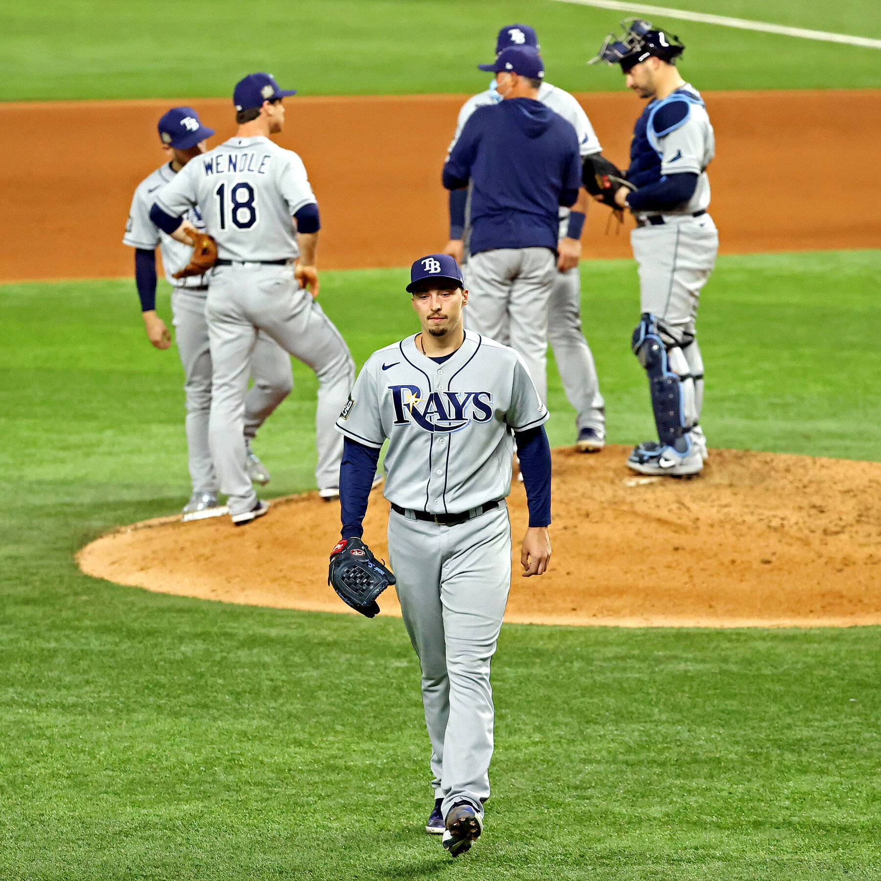 Blake Snell 桌布 壁紙 — 一名坦帕灣光芒隊的投手走下投手丘，隊友和捕手在燈光明亮的棒球場本壘板附近聚集。