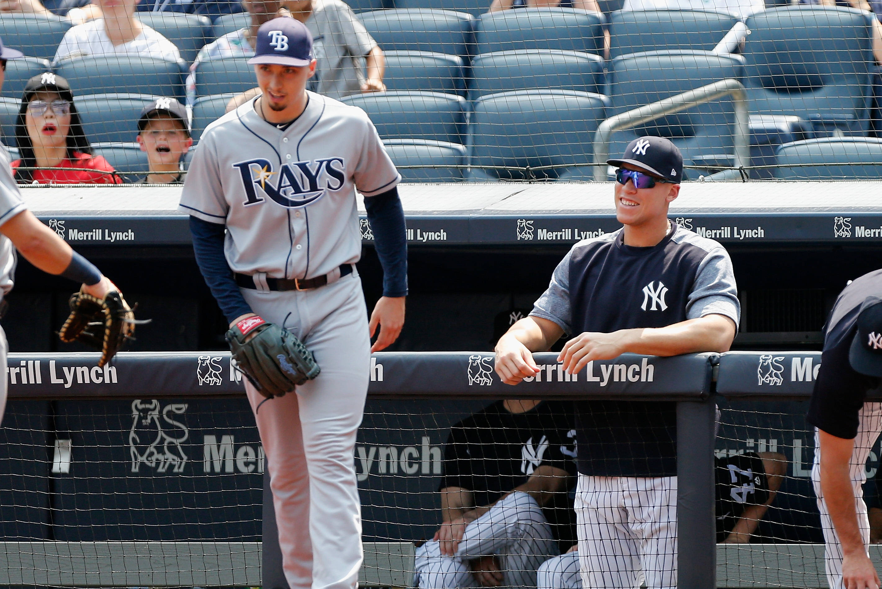 Blake Snell 桌布 壁紙 — 一名坦帕灣光芒隊的棒球選手在陽光明媚的比賽中走過一名微笑的紐約洋基隊選手在休息區。