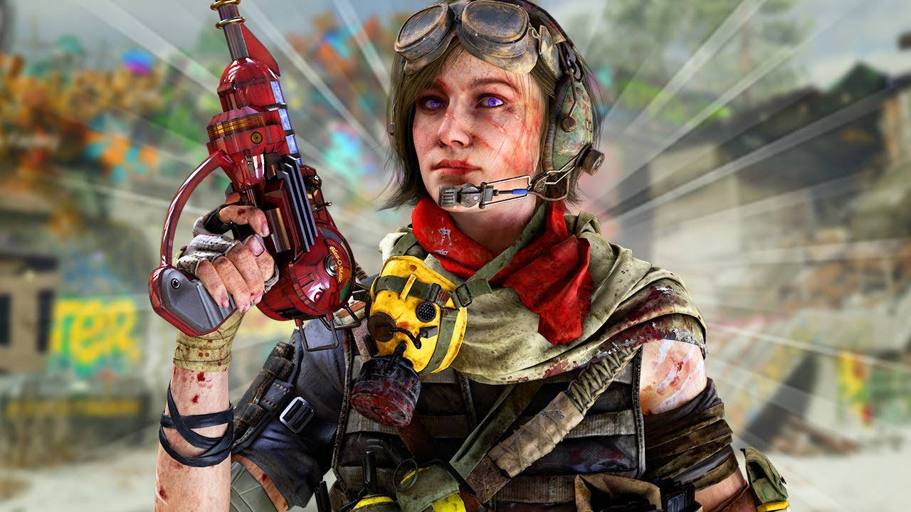 Maxis 桌布 壁紙 — 一名堅毅的女兵戴著護目鏡和紅色武器，站在一個佈滿塗鴉和瓦礫的戰亂城市廢墟中。