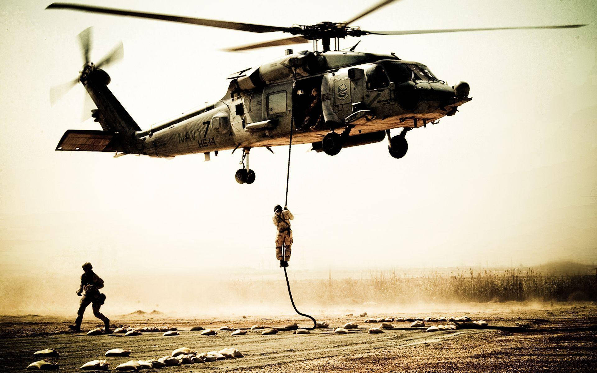 Black Hawk Helicopter 桌布 壁紙 — 一名士兵從懸停的軍用直升機上繩降，另一名士兵在塵土飛揚的沙漠跑道上向他跑來。