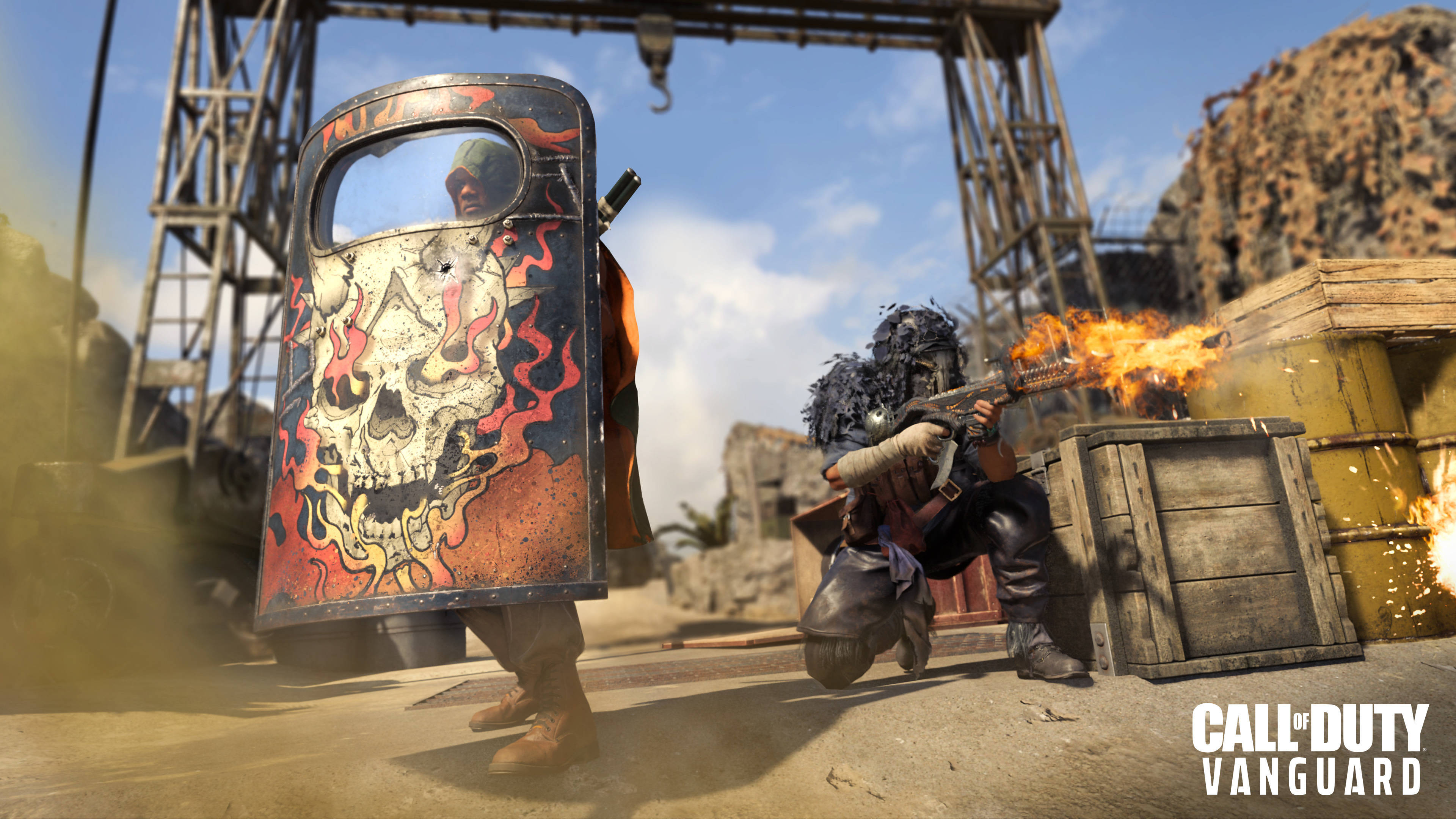 Call Of Duty Vanguard 桌布 壁紙 — 一名士兵手持火焰骷髏盾牌前進，另一名士兵在晴朗天空下的工業廢墟中開火。