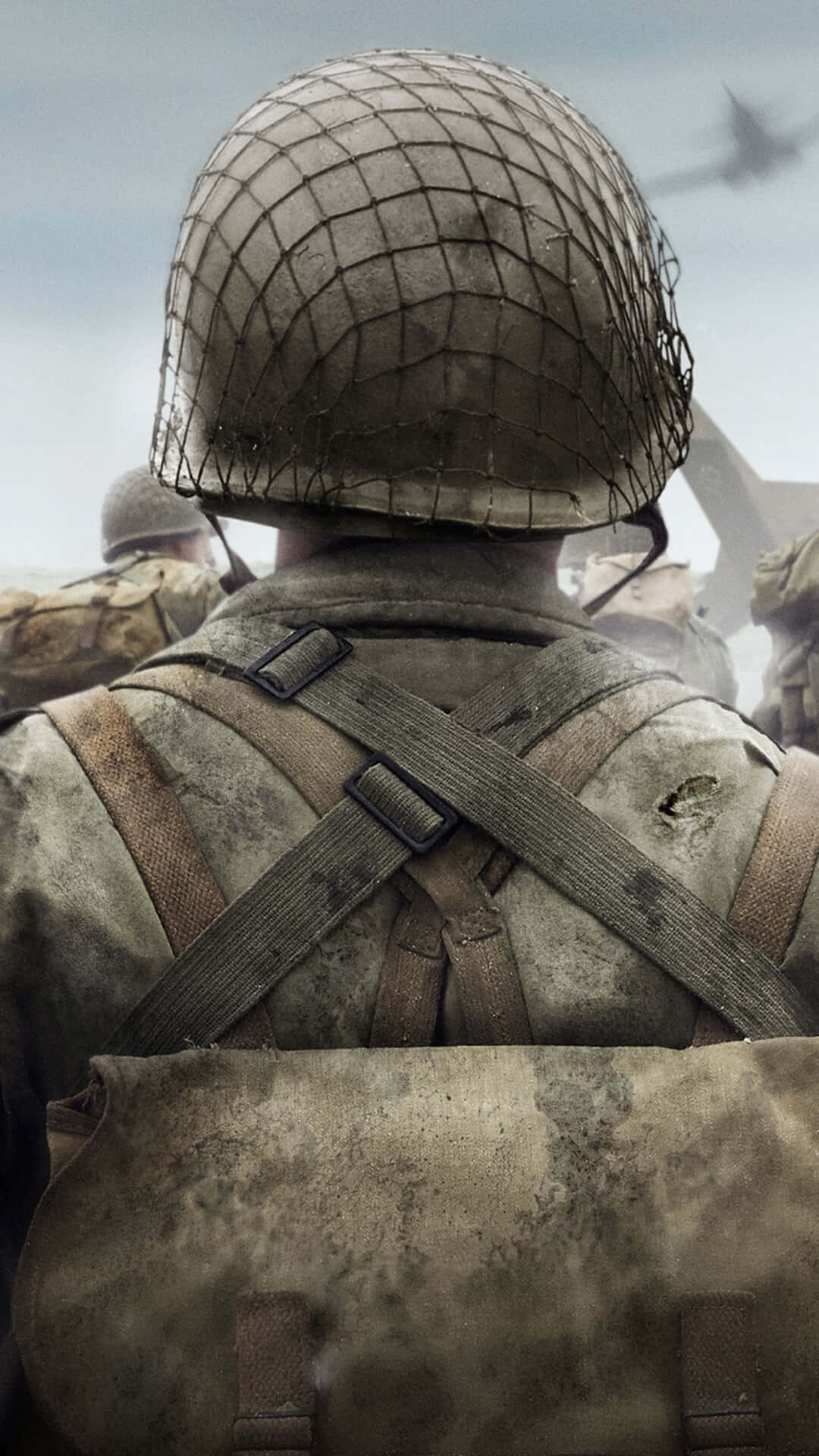 Ww2 iPhone 桌布 壁紙 — 一名士兵身穿破舊頭盔和裝備，在陰天天空下望向遠處飛機的背影。