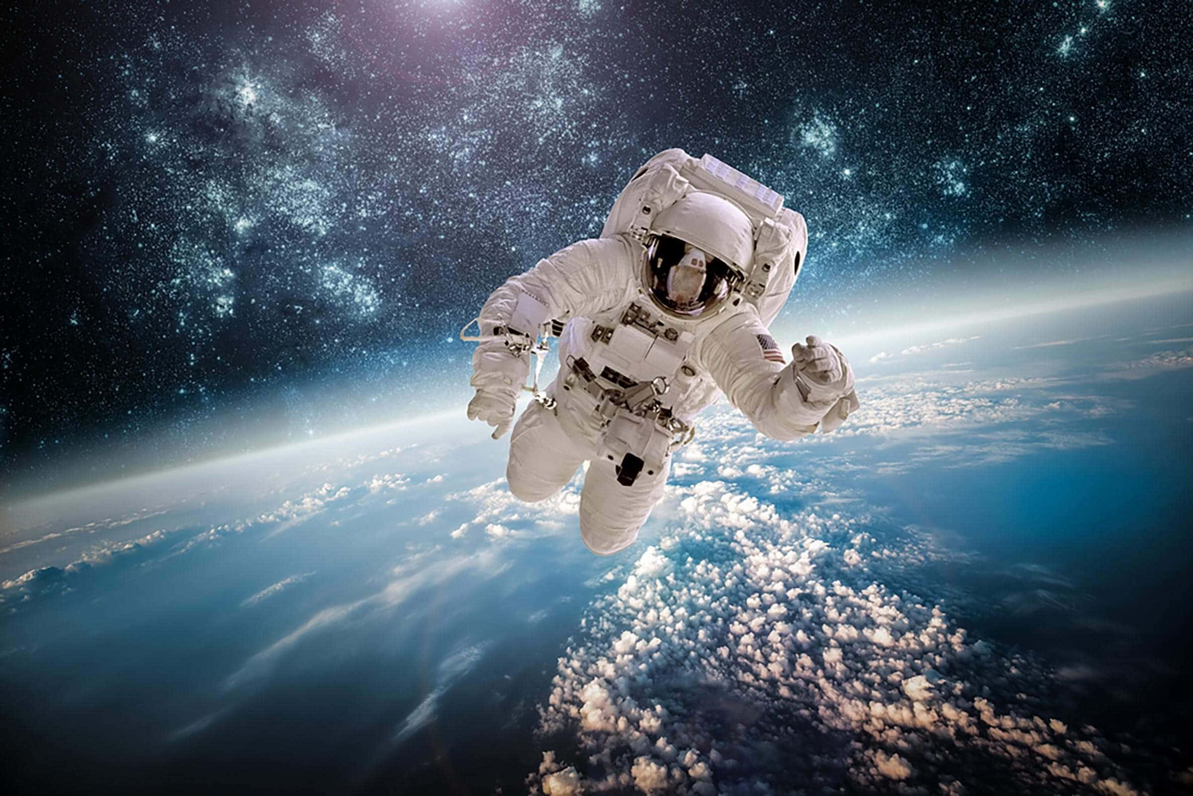 太空 桌布 壁紙 — 一名太空人在佈滿星星的宇宙背景下，在雲層覆蓋的地球表面上方無重漂浮。