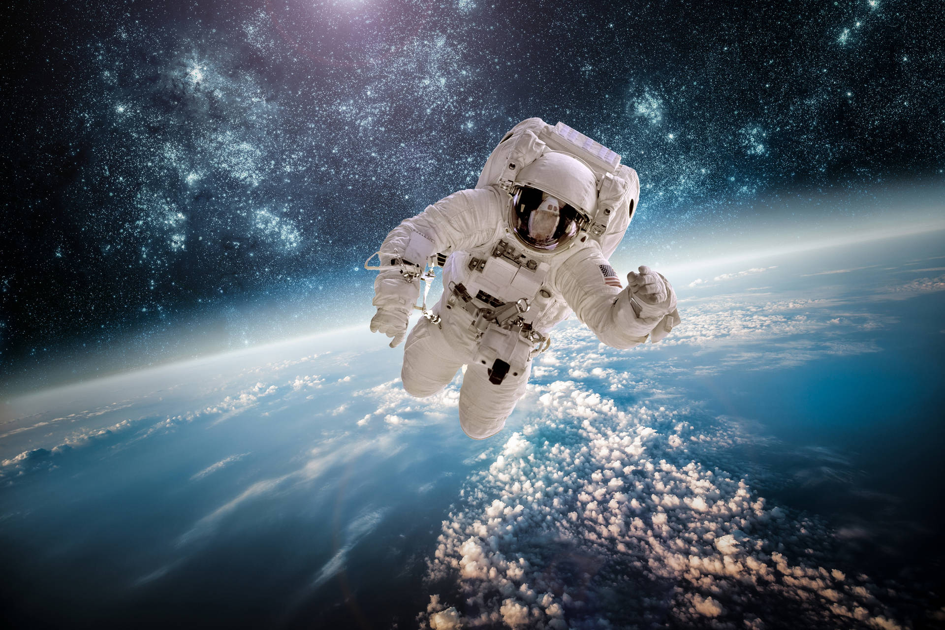  壁紙 — 一名太空人在佈滿星星的宇宙背景下，無重狀態地漂浮在地球被雲層覆蓋的藍色表面之上。