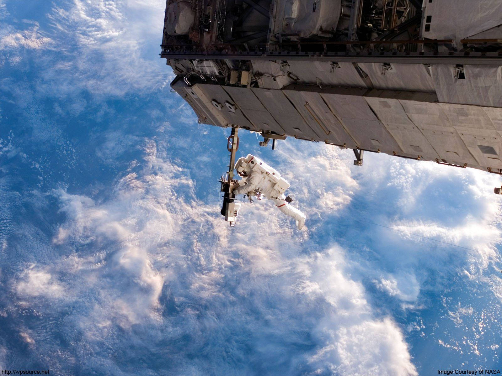NASA 動態圖片 桌布 壁紙 — 一名太空人在國際太空站外漂浮，背景是地球的藍色海洋和白色雲層。