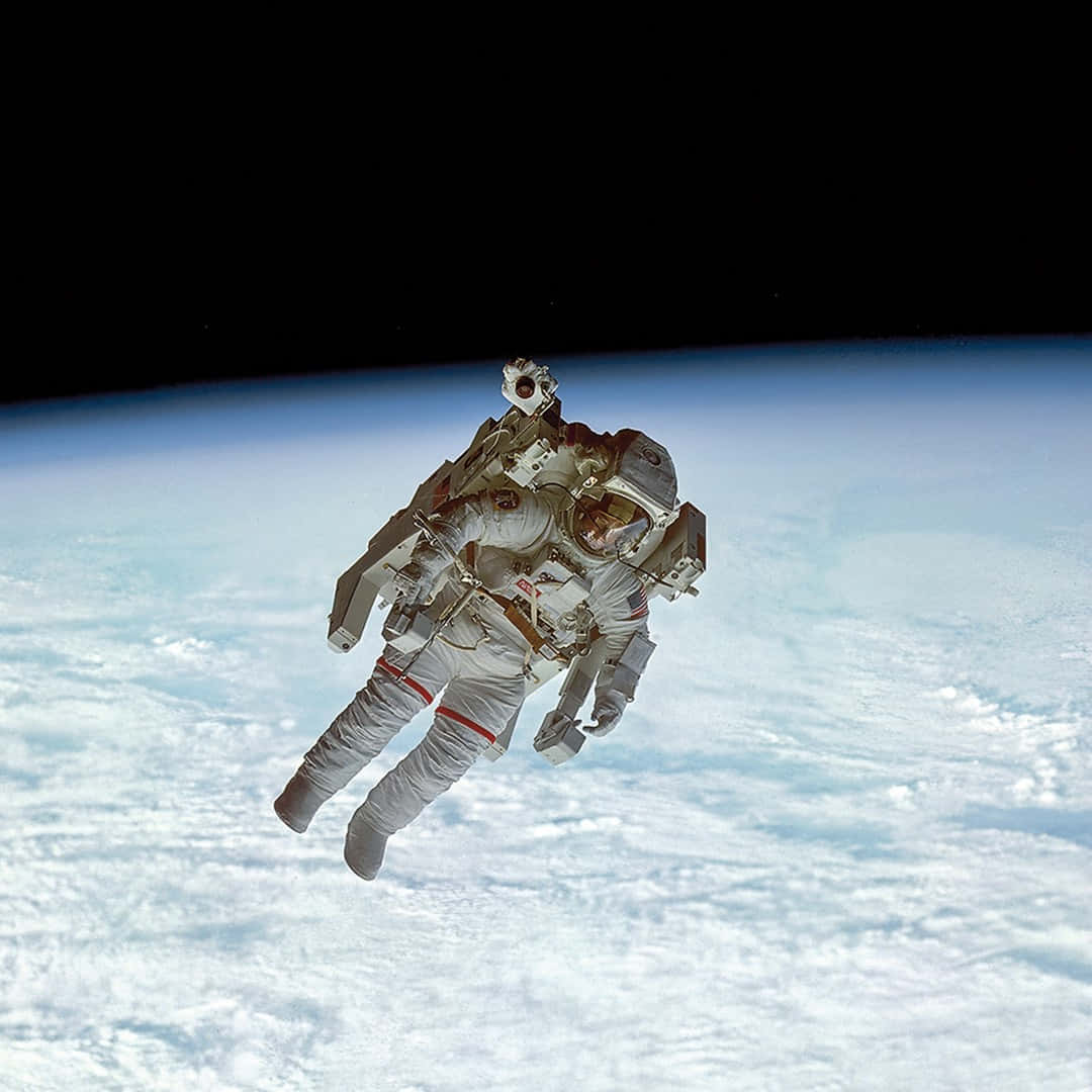太空 桌布 壁紙 — 一名太空人在地球彎曲的地平線上方，在太空的黑色虛空中失重漂浮。