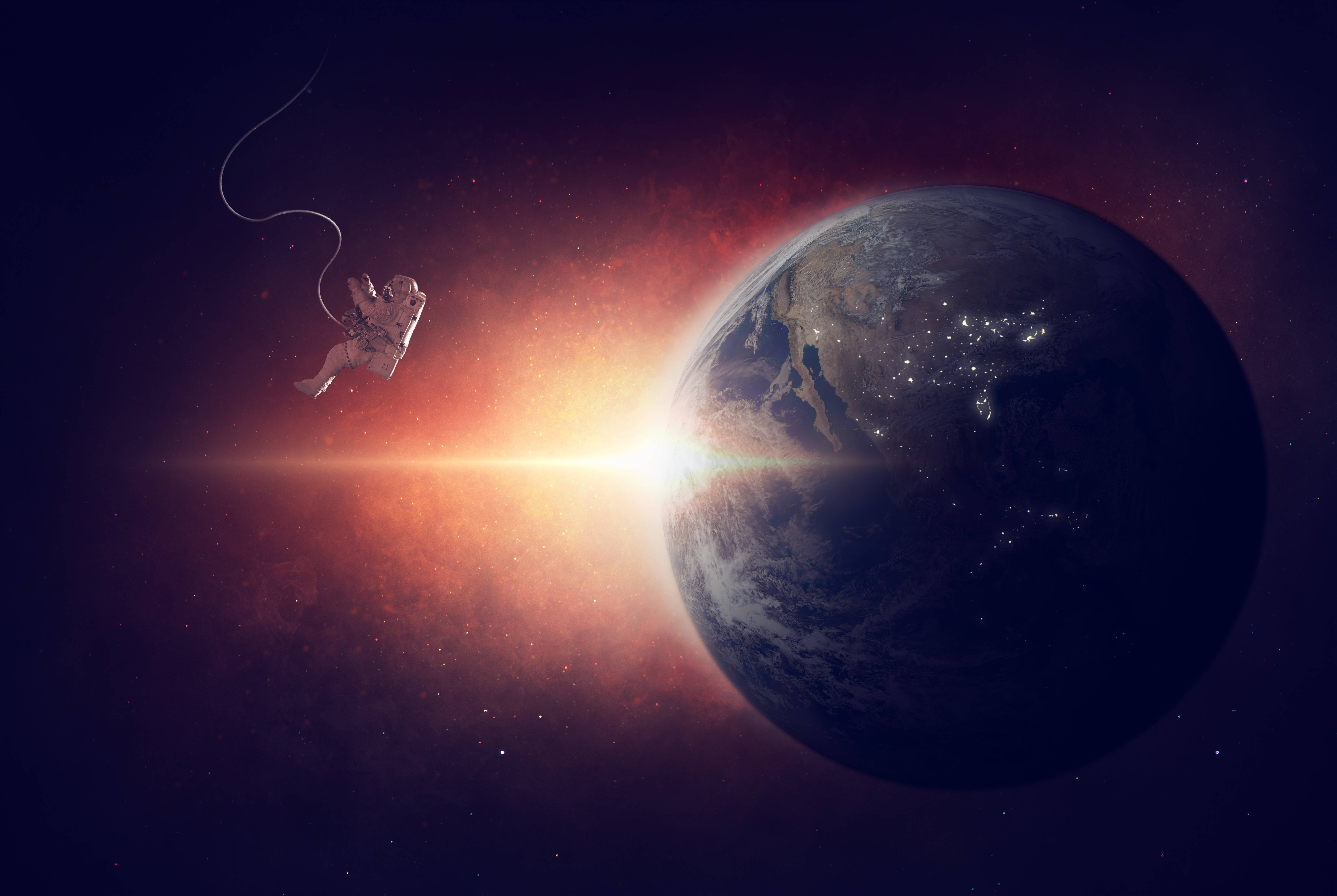 太空人 桌布 壁紙 — 一名太空人在太空中漂浮，被纜繩繫著，靠近因城市燈光而發光的地球，背景是熾熱的宇宙。