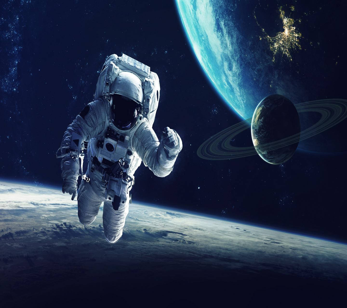 太空人 桌布 壁紙 — 一名太空人在太空漂浮，地球和土星在宇宙背景中可見。