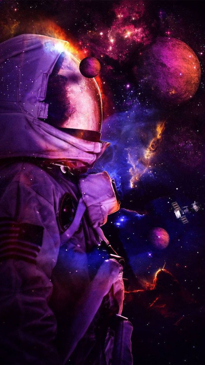 酷炫星系 桌布 壁紙 — 一名太空人在色彩繽紛的星雲和行星之間漂浮，頭盔反射著宇宙的光芒。