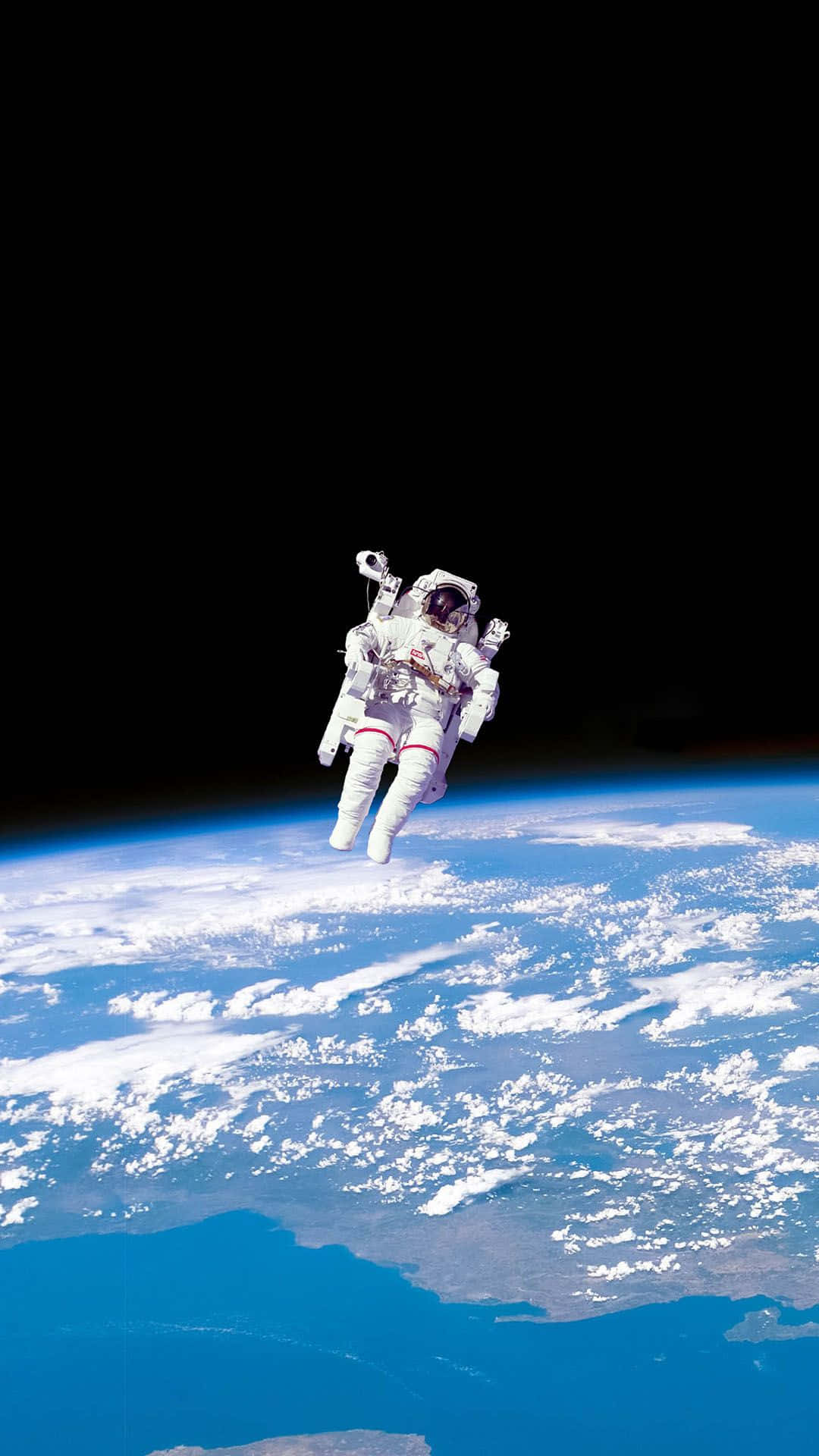  壁紙 — 一名太空人在黑色太空的背景下，在彎曲的藍白色地球表面上方失重漂浮。