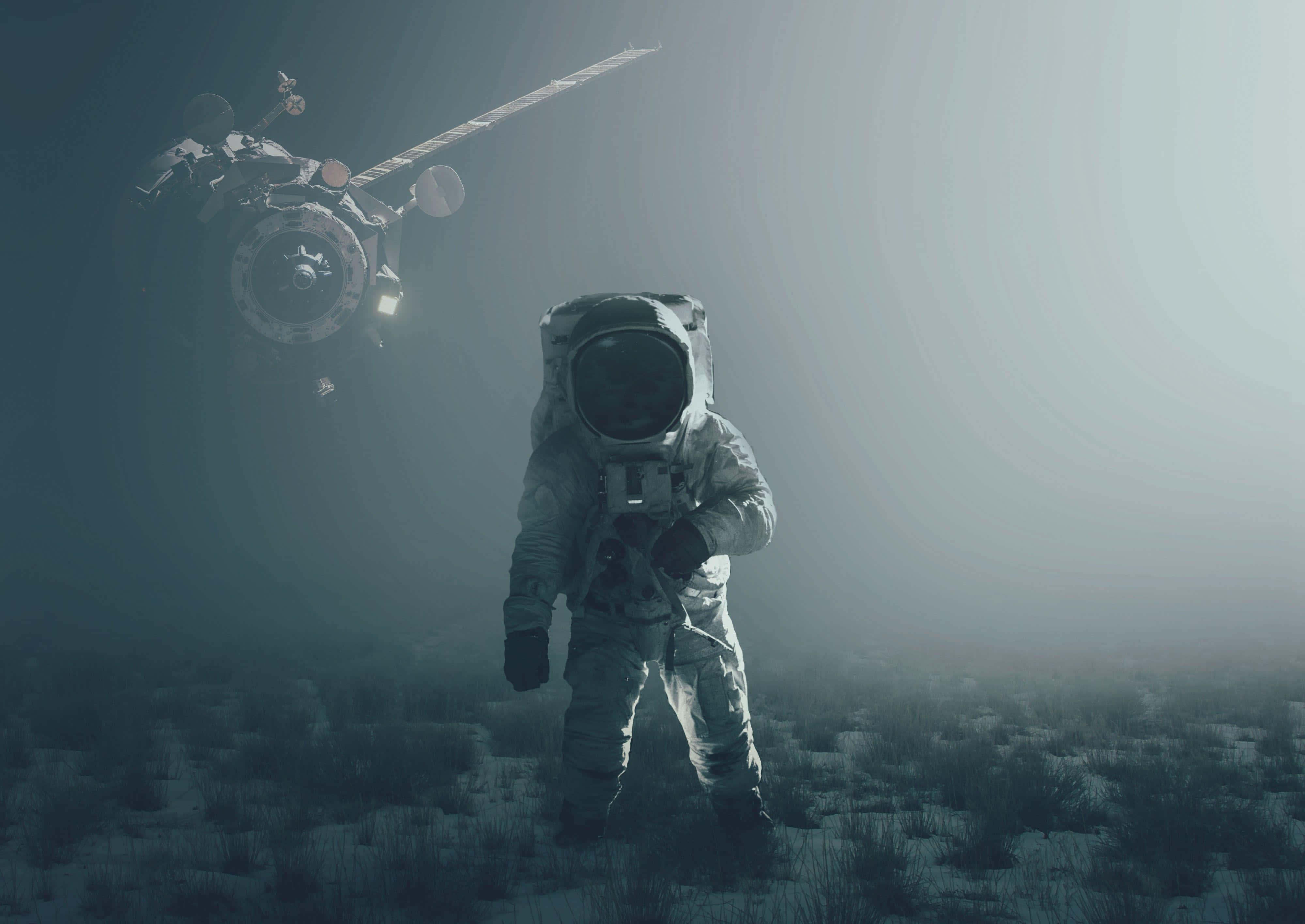 Astronaut Desktop 桌布 壁紙 — 一名太空人獨自站在荒蕪的外星景觀中，一艘太空船在迷霧背景中盤旋。