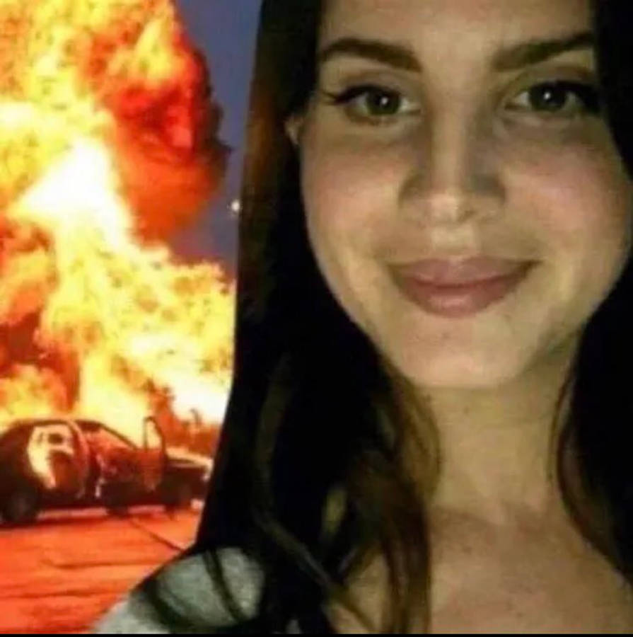 meme 桌布 壁紙 — 一名女子在戲劇性場景中，對著吞噬汽車的猛烈爆炸微笑。