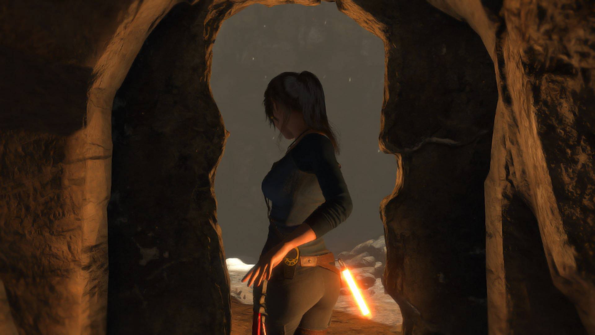 Rise Of The Tomb Raider 桌布 壁紙 — 一名女子站在岩石洞穴入口，手持發光的火炬，凝視著星空下白雪皚皚的景色。