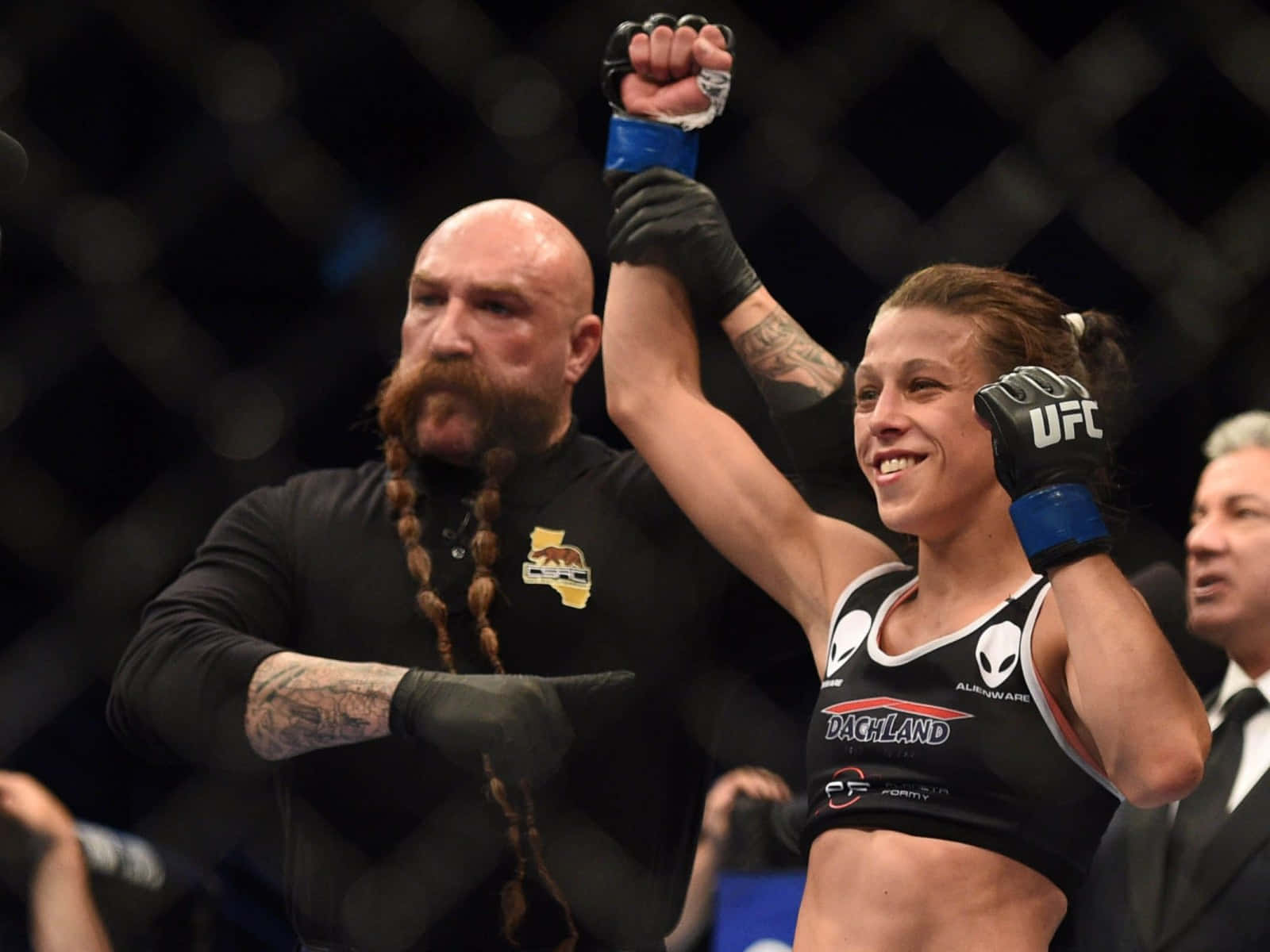 professional 桌布 壁紙 — 一名女性MMA拳手在八角籠內被裁判宣佈為勝者時，勝利地舉起拳頭。
