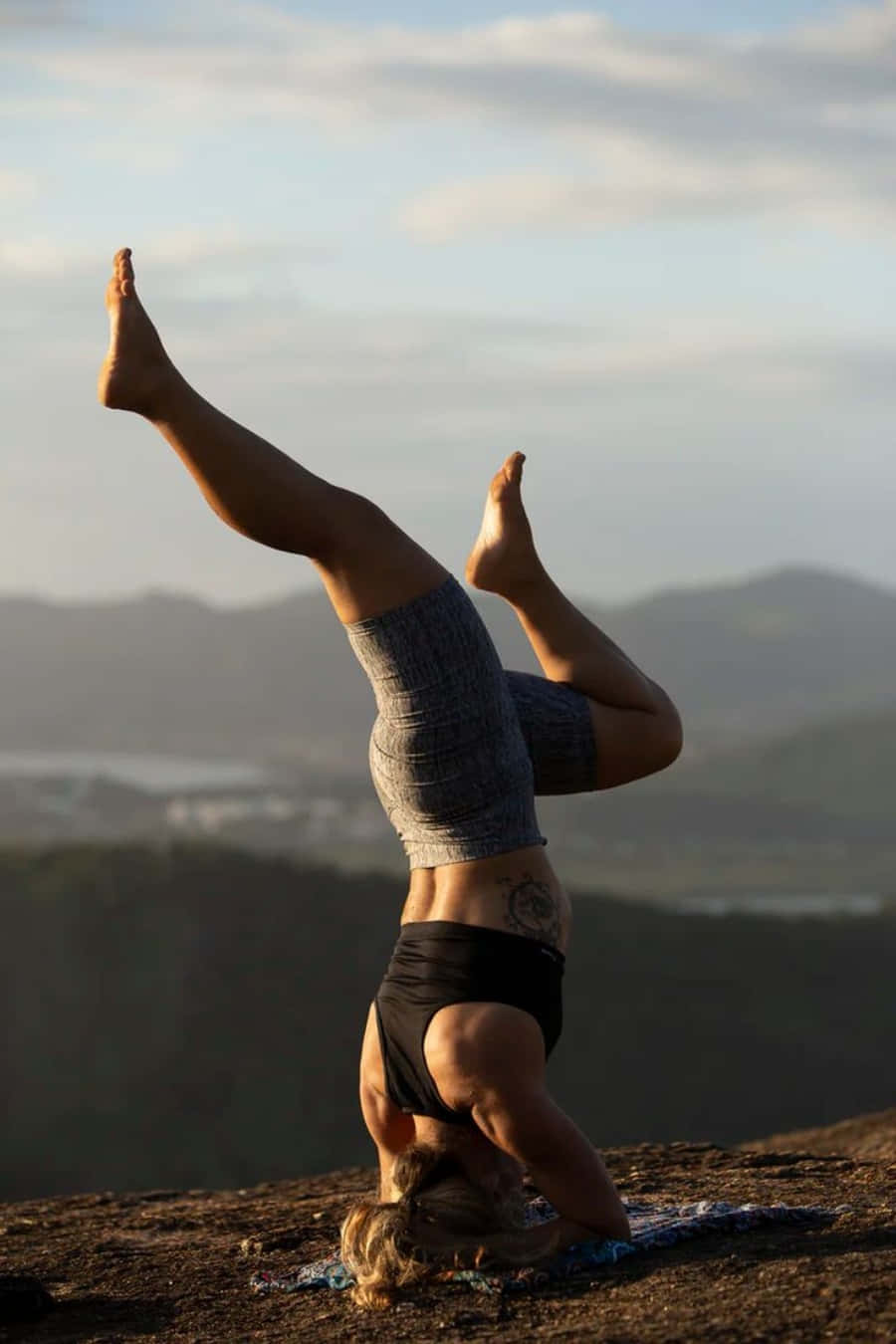Fitness 桌布 壁紙 — 一名女性在岩石懸崖上做頭倒立，俯瞰霧氣瀰漫的山谷，正值黃金時刻。