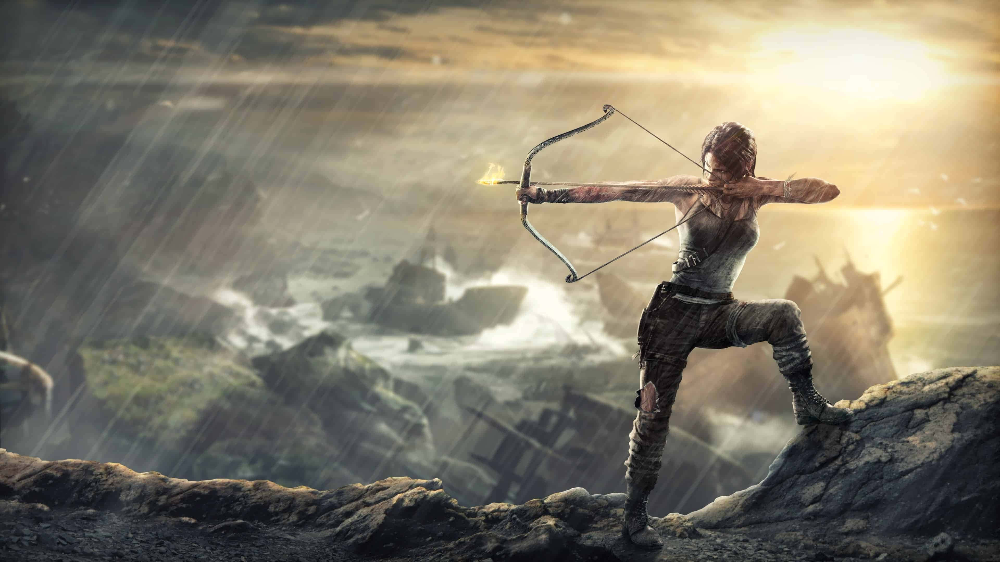 Lara Croft 桌布 壁紙 — 一名女戰士在暴風雨懸崖頂上拉弓搭箭，箭矢燃燒，身後夕陽在沉船上方燃燒。