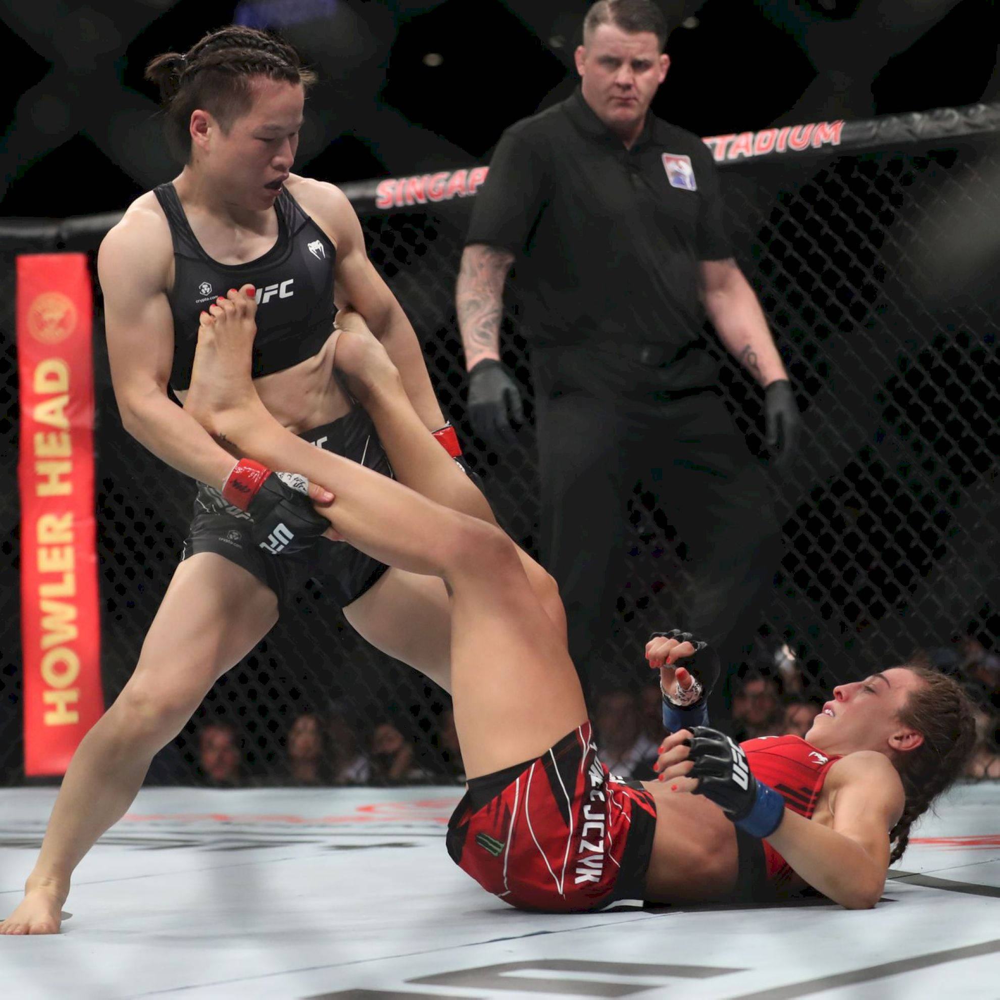 MMA 桌布 壁紙 — 一名女拳手在UFC八角籠內對對手施展腳鎖，裁判在旁緊密觀察。