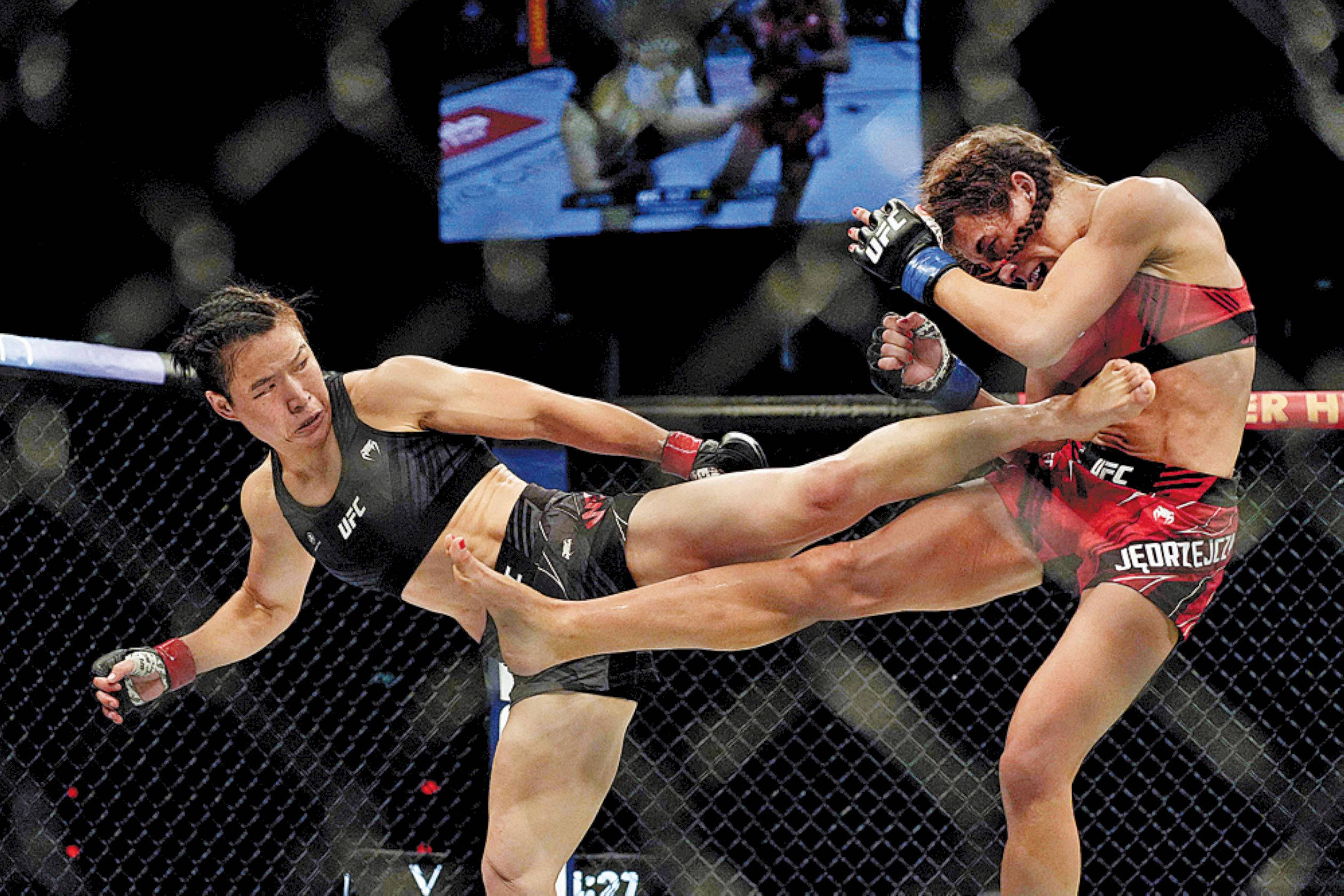 Fight 桌布 壁紙 — 一名女拳手在明亮的場館燈光下，於UFC八角籠中向對手踢出高踢。