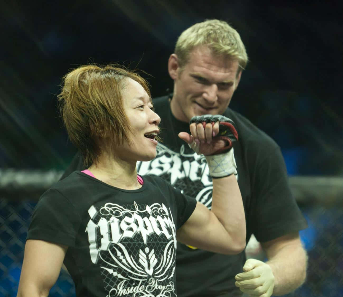 UFC 桌布 壁紙 — 一名女拳手在籠中慶祝勝利，身後有一位微笑的教練。