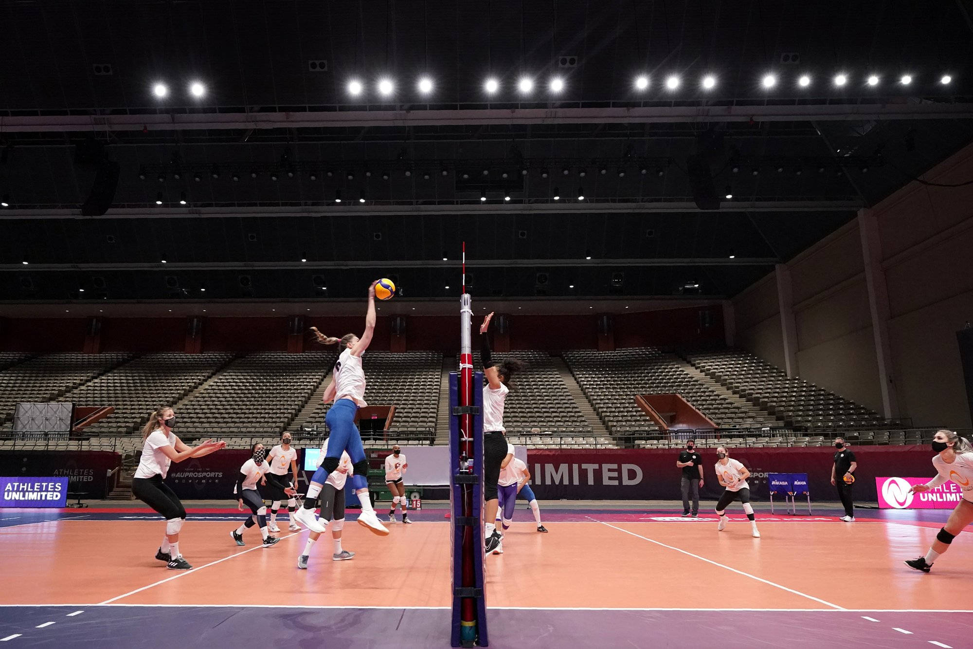 Indoor Volleyball 桌布 壁紙 — 一名女排球員高高躍起，在空無一人的室內場館中將球扣過網。