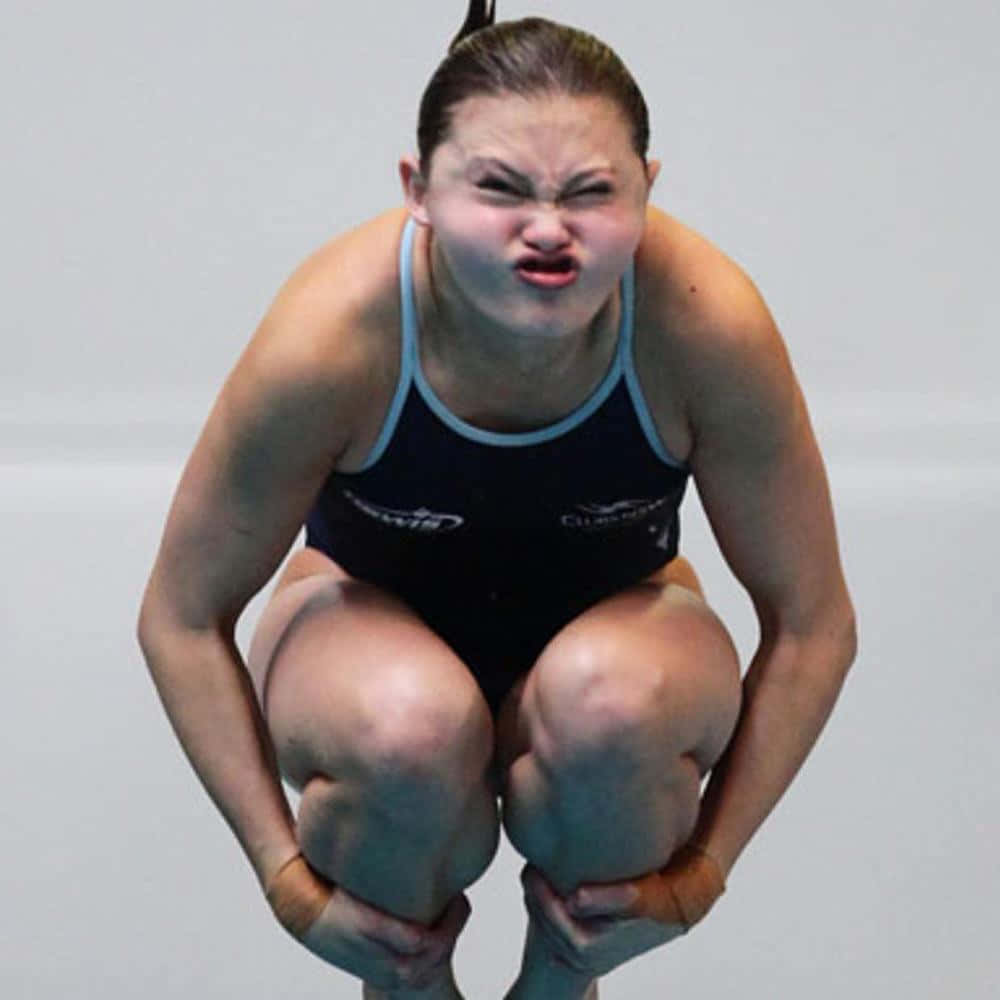 diving 桌布 壁紙 — 一名女潛水員在跳板上蹲下，專注而表情兇猛，準備跳躍。