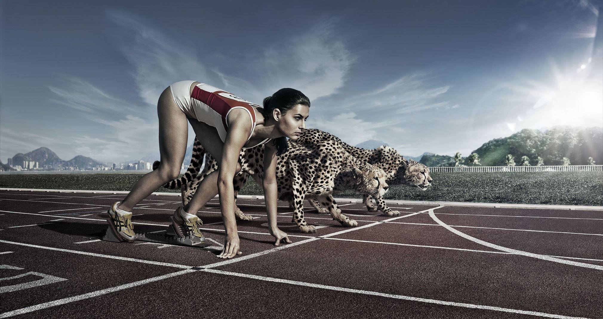 HD Sports 桌布 壁紙 — 一名女短跑運動員和三隻獵豹在明亮的陽光下，遠處有山脈，蹲在跑道起點線上。