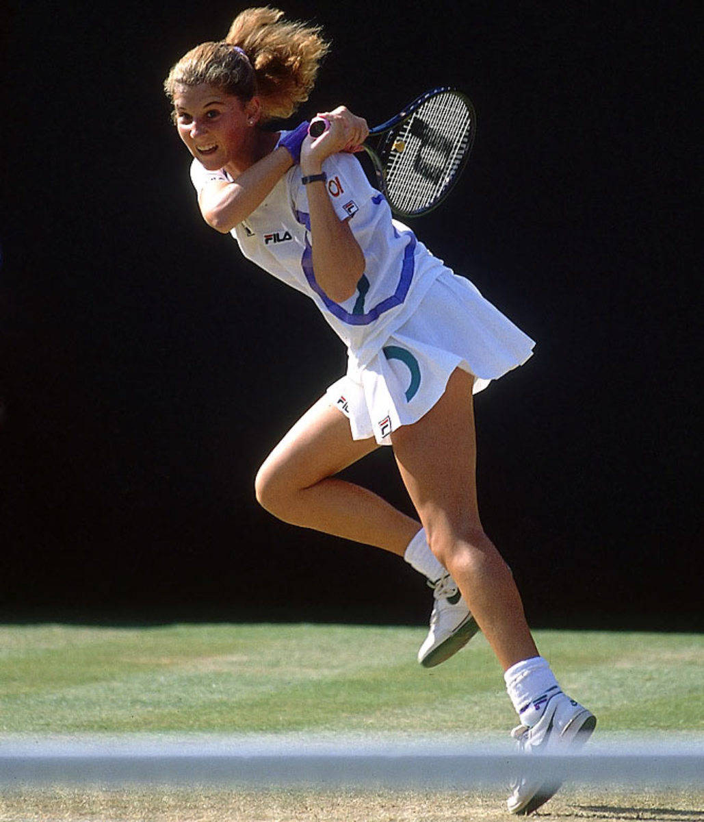 Monica Seles 桌布 壁紙 — 一名女網球運動員在明亮的日光下於草地場上跳起揮拍，專注力十足。