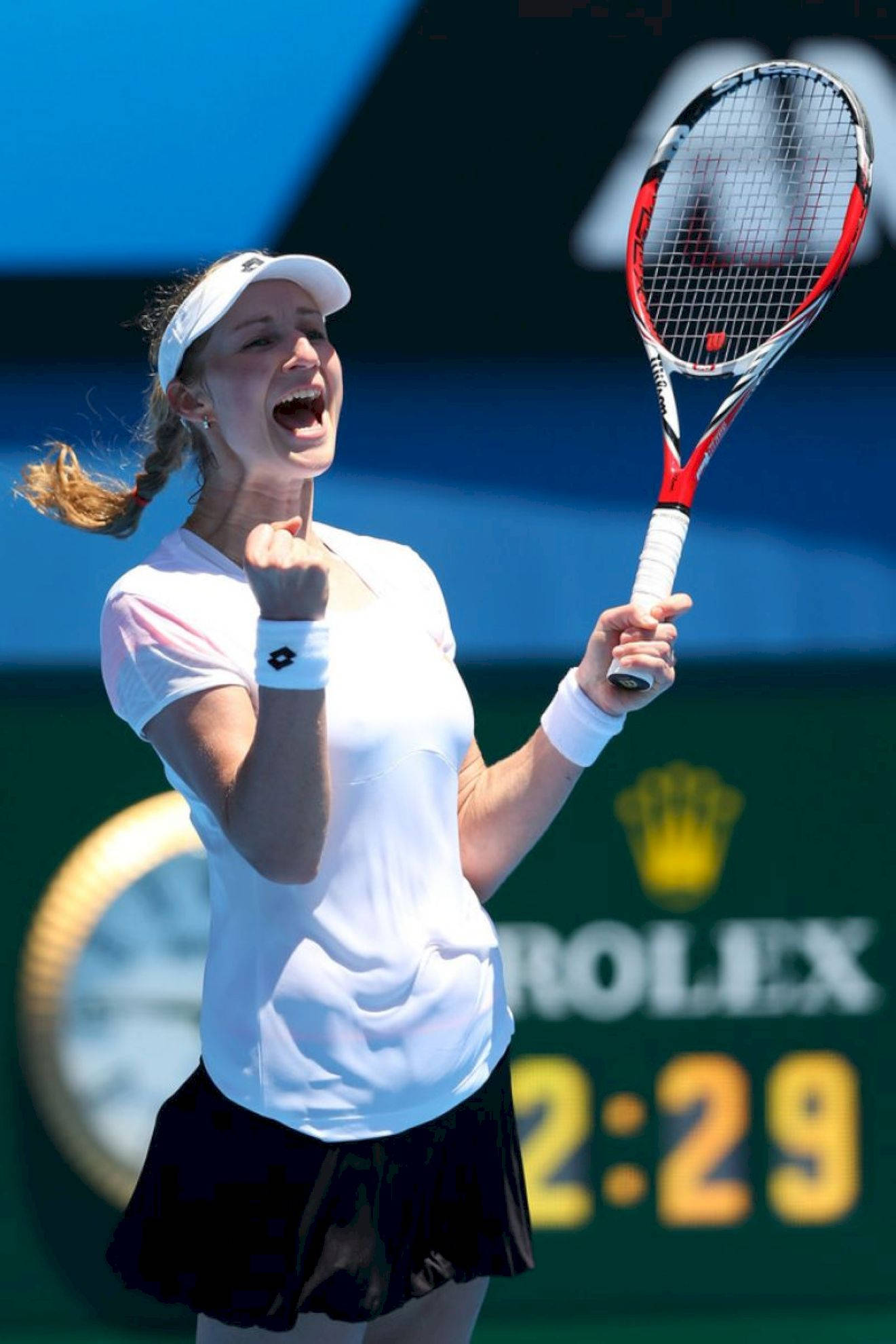 Tennis 桌布 壁紙 — 一名女網球運動員在明亮的日光下舉起拳頭和球拍慶祝勝利。