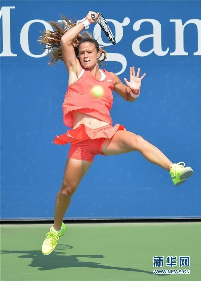 Athlete 桌布 壁紙 — 一名女網球運動員在藍色牆壁背景下跳躍空中，做出動態的正手揮拍動作。