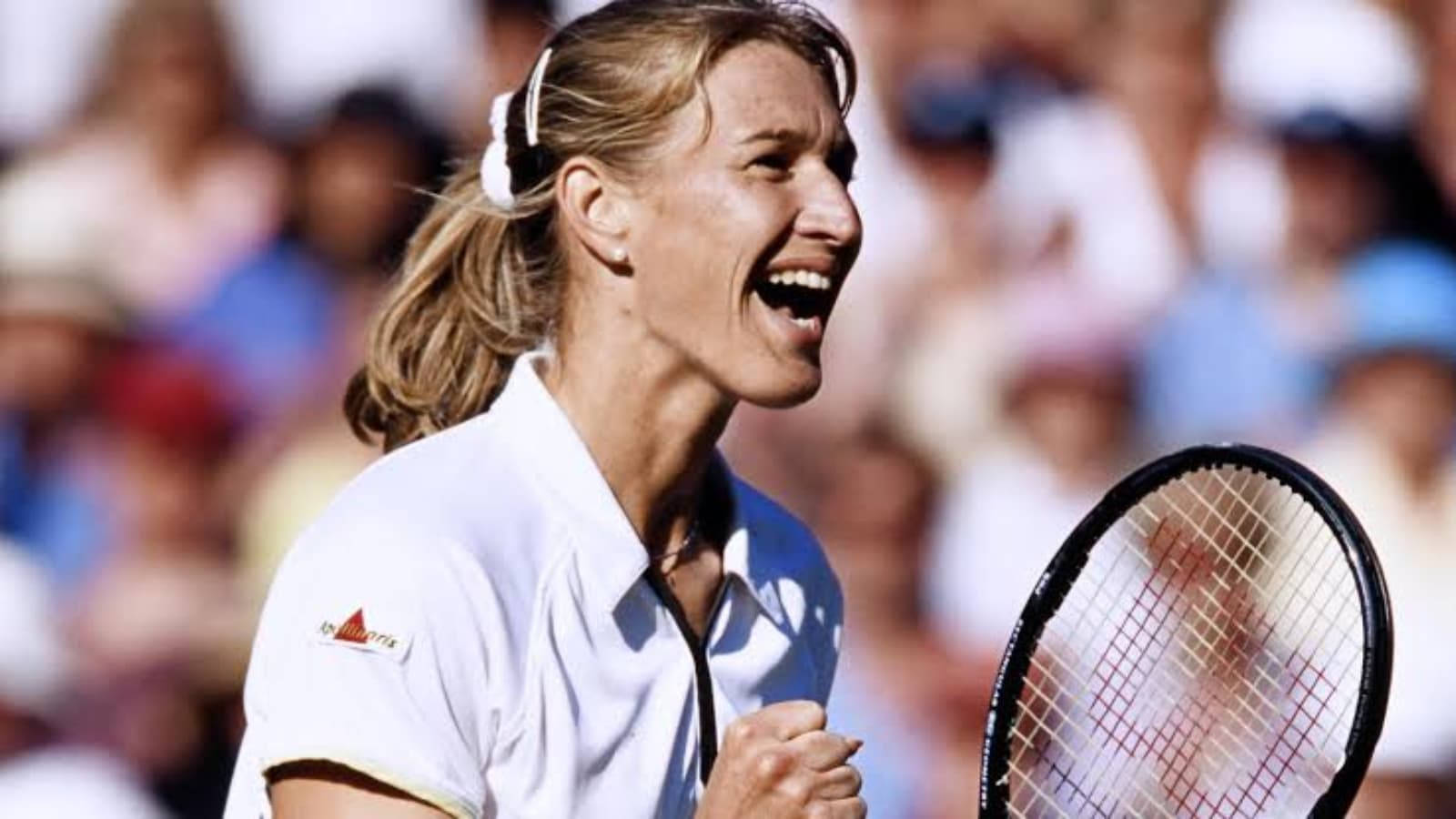 Tennis 桌布 壁紙 — 一名女網球運動員在陽光明媚的球場上握緊拳頭，歡呼雀躍，高舉球拍慶祝勝利。