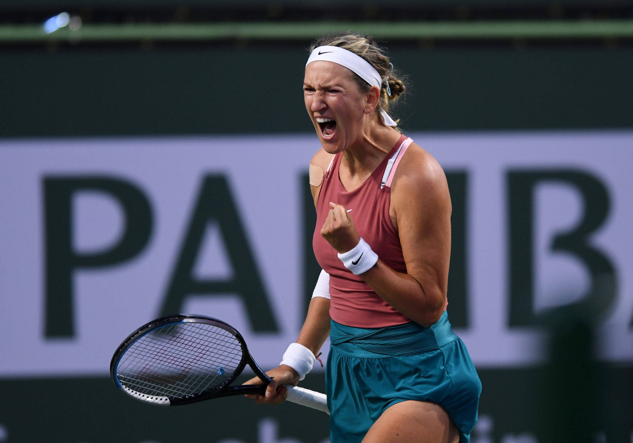 Athletic 桌布 壁紙 — 一名女網球選手在球場上握著球拍，高舉拳頭，發出勝利的吶喊。