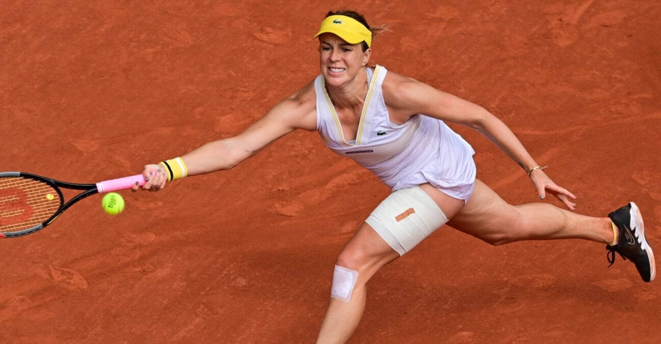 Athletic 桌布 壁紙 — 一名女網球選手在紅土球場上向前猛衝，以高度專注力擊打一顆亮黃色的球。