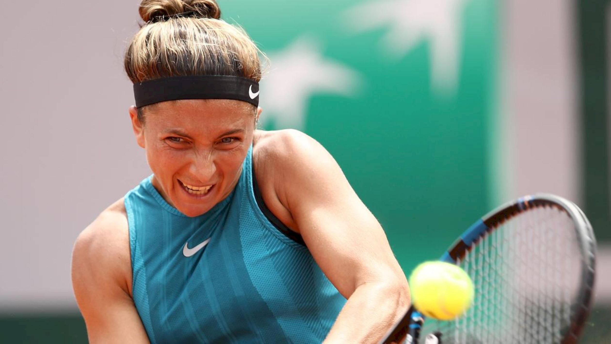 Nike 桌布 壁紙 — 一名女網球選手在紅土球場上揮拍擊打黃色網球，表情繃緊，專注力極強。