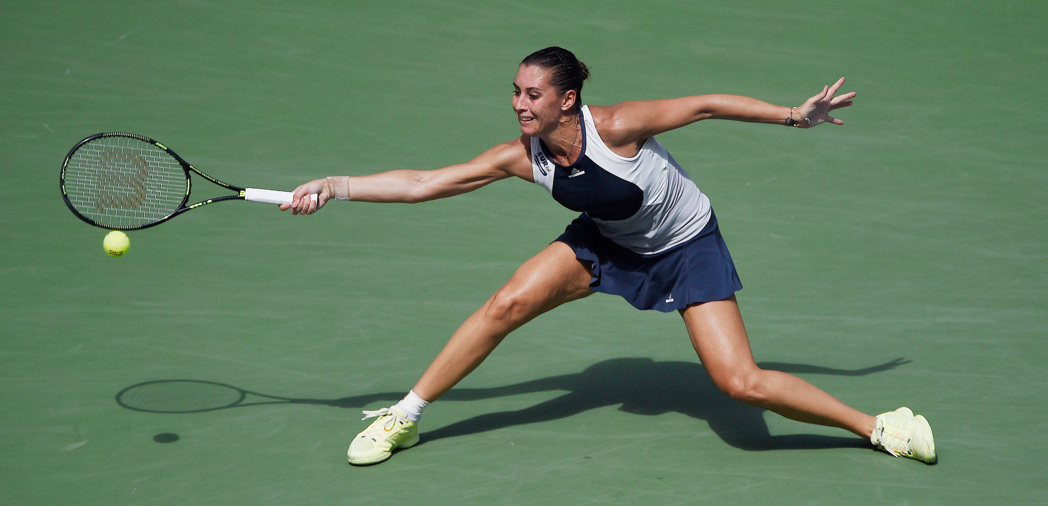 Athletic 桌布 壁紙 — 一名女網球選手在綠色球場上向前猛衝，以高度專注和運動能力擊出正手拍。