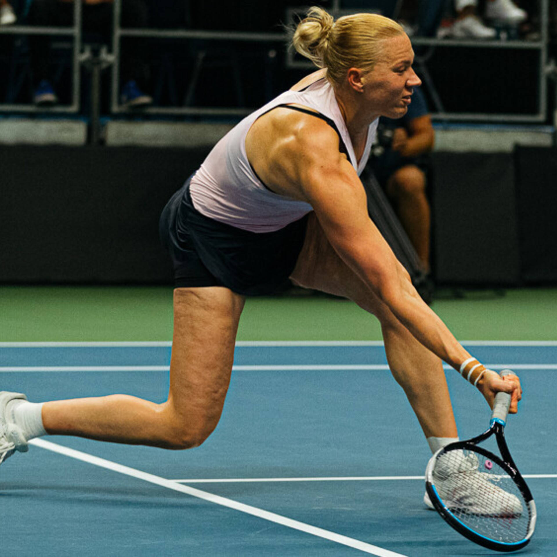 Tennis 桌布 壁紙 — 一名女網球選手在藍色球場上低身撲球，緊握球拍，專注力十足。