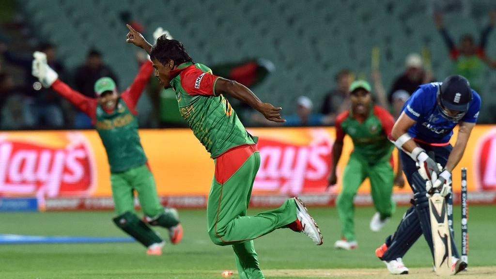 Bangladesh Cricket 桌布 壁紙 — 一名孟加拉國板球投球手在夜間球場燈光下慶祝一個三柱門，而一名英格蘭擊球手倒下。