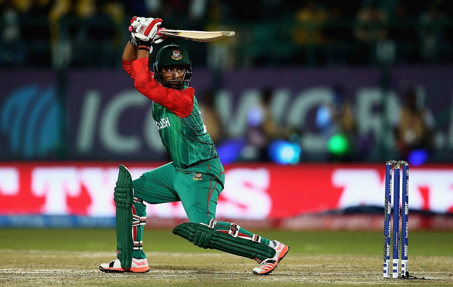 Bangladesh Cricket 桌布 壁紙 — 一名孟加拉國板球擊球手身穿綠色制服，在體育場燈光下的夜間比賽中強力揮棒。
