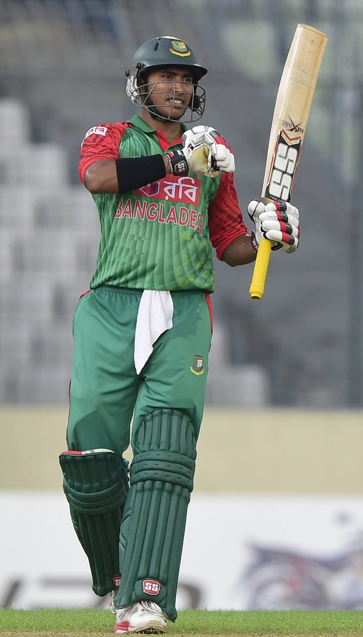 Bangladesh Cricket 桌布 壁紙 — 一名孟加拉國板球運動員身穿綠色制服，在草地上微笑著手持球棒。