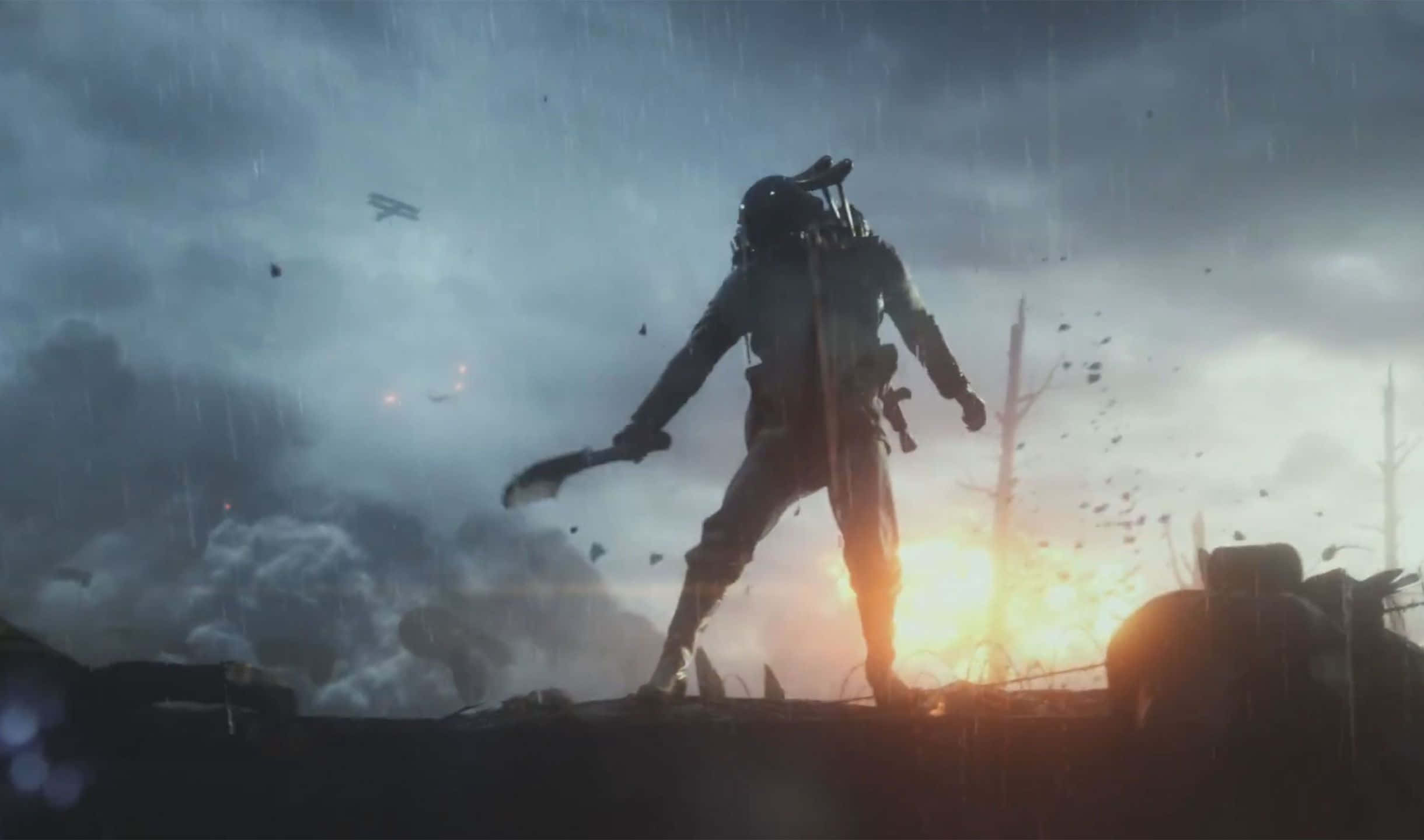 2440x1440 Battlefield 1 桌布 壁紙 — 一名孤獨的士兵在雨淋的戰場上，以火紅的夕陽為背景，形成剪影，周圍有爆炸和墜落的碎片。