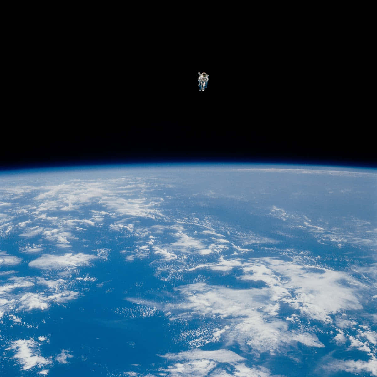 太空 桌布 壁紙 — 一名孤獨的太空人在地球彎曲的藍色地平線上方漂浮，背景是太空的黑色虛空。