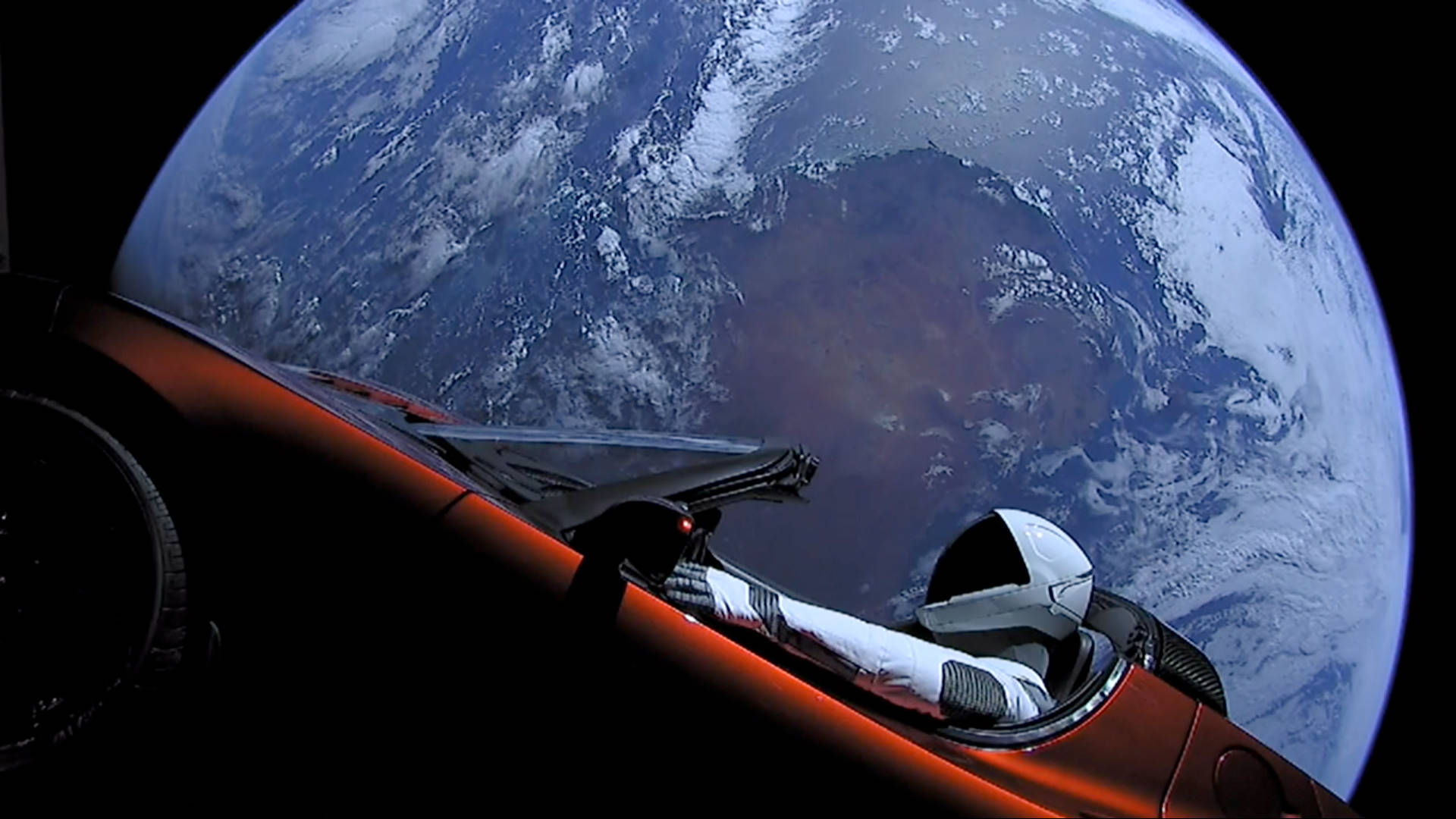 Astronaut In Space 桌布 壁紙 — 一名孤獨的太空人坐在流線型紅色太空船中，從太空的黑色虛空凝視著地球旋轉的藍白雲層。