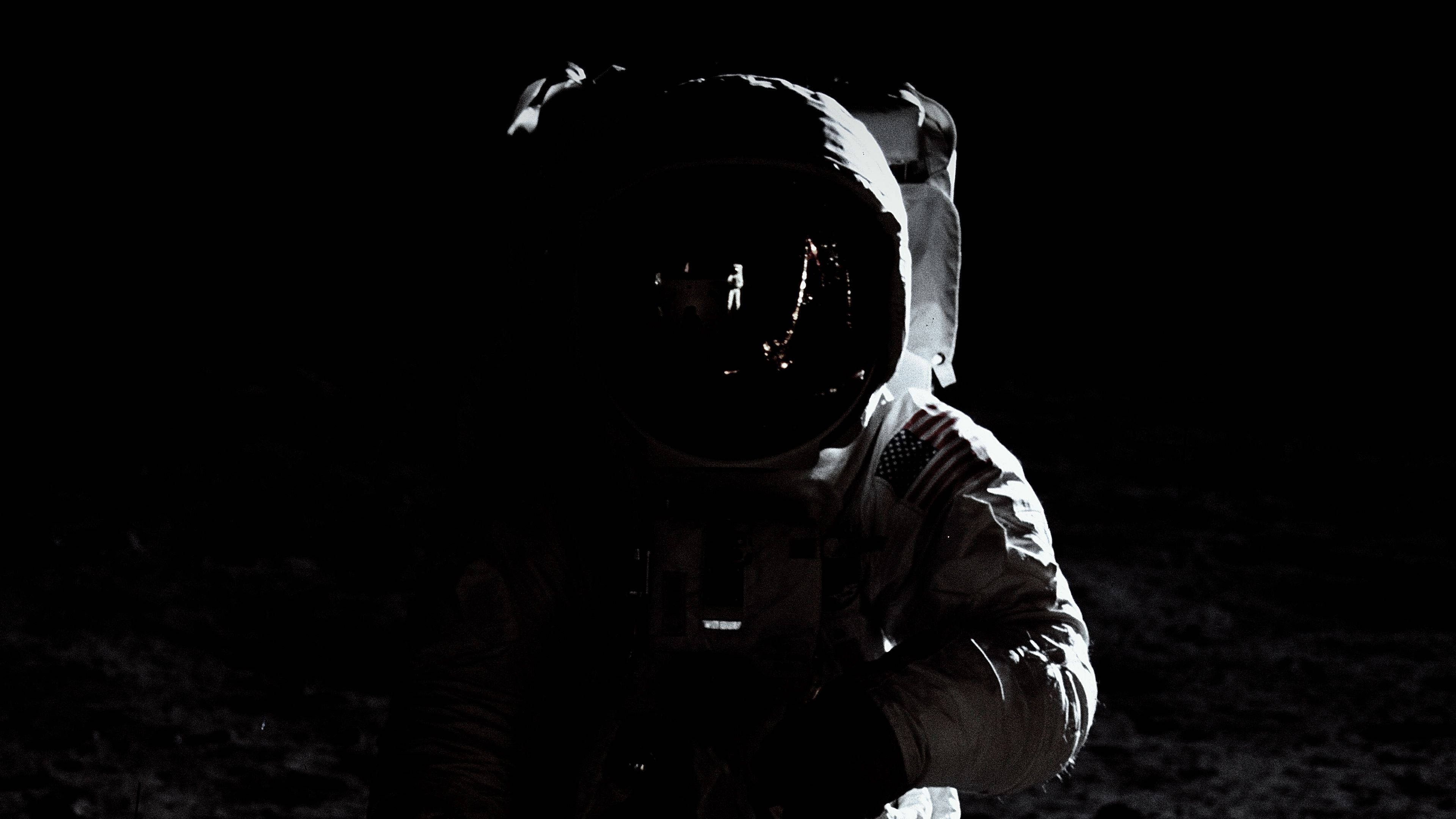 astronaut aesthetic 桌布 壁紙 — 一名孤獨的太空人穿著太空衣站在月球表面，背景是漆黑虛空，只有頭盔反射在發光。