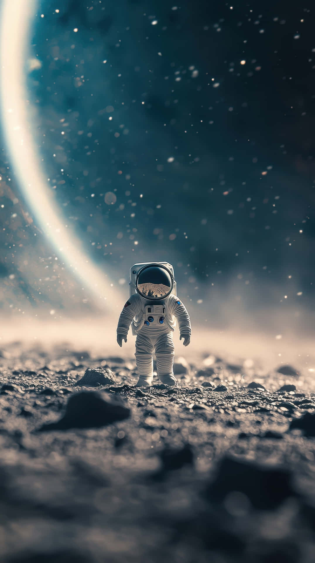 Miniature Astronaut on an Rocky Alien Terrain Under a Cosmic Glow 壁紙 — 一名孤獨的太空人站在岩石外星行星上，下方是巨大發光的環狀行星，上方是繁星點點的夜空。