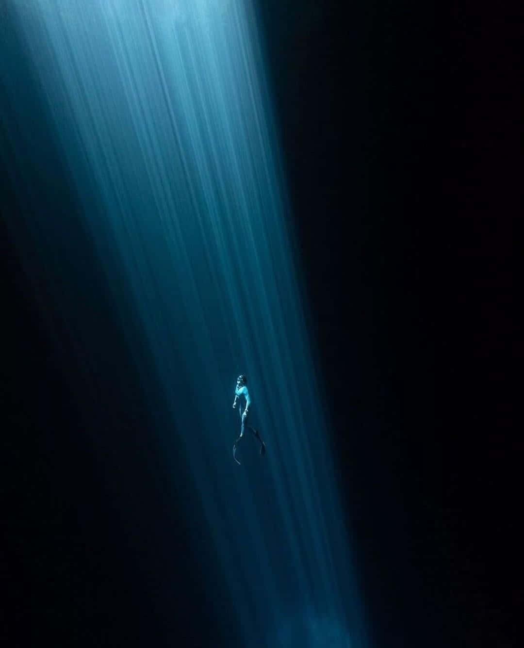 Scary Underwater 桌布 壁紙 — 一名孤獨的水肺潛水員在水下寧靜地漂浮，上方陽光穿透深藍色的海洋。