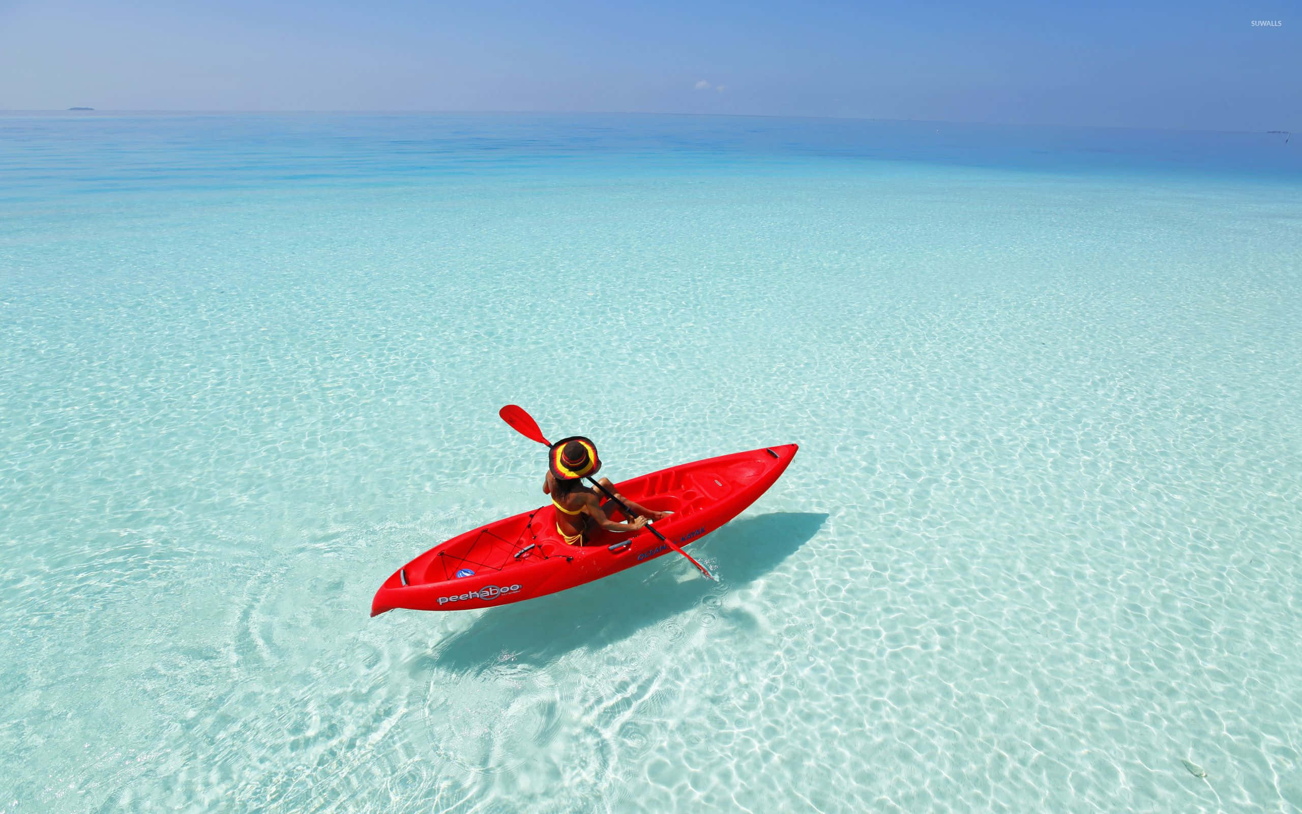 Maldives Beach 桌布 壁紙 — 一名孤獨的皮划艇運動員划著鮮紅色的皮划艇，在晴朗的藍天下穿越清澈碧綠的海水。