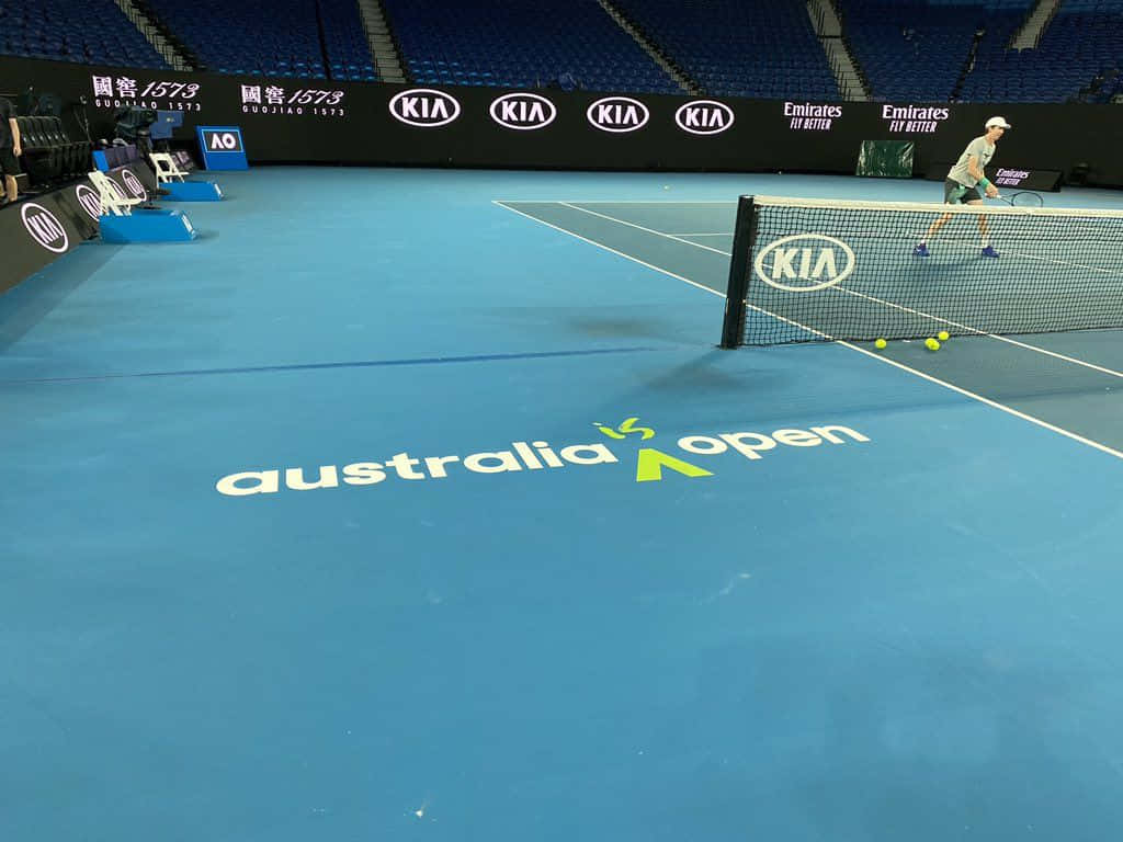 Australian Open 桌布 壁紙 — 一名孤獨的網球選手在澳洲網球公開賽充滿活力的藍色硬地球場上練習，背景有贊助商標誌和空無一人的體育場座位。